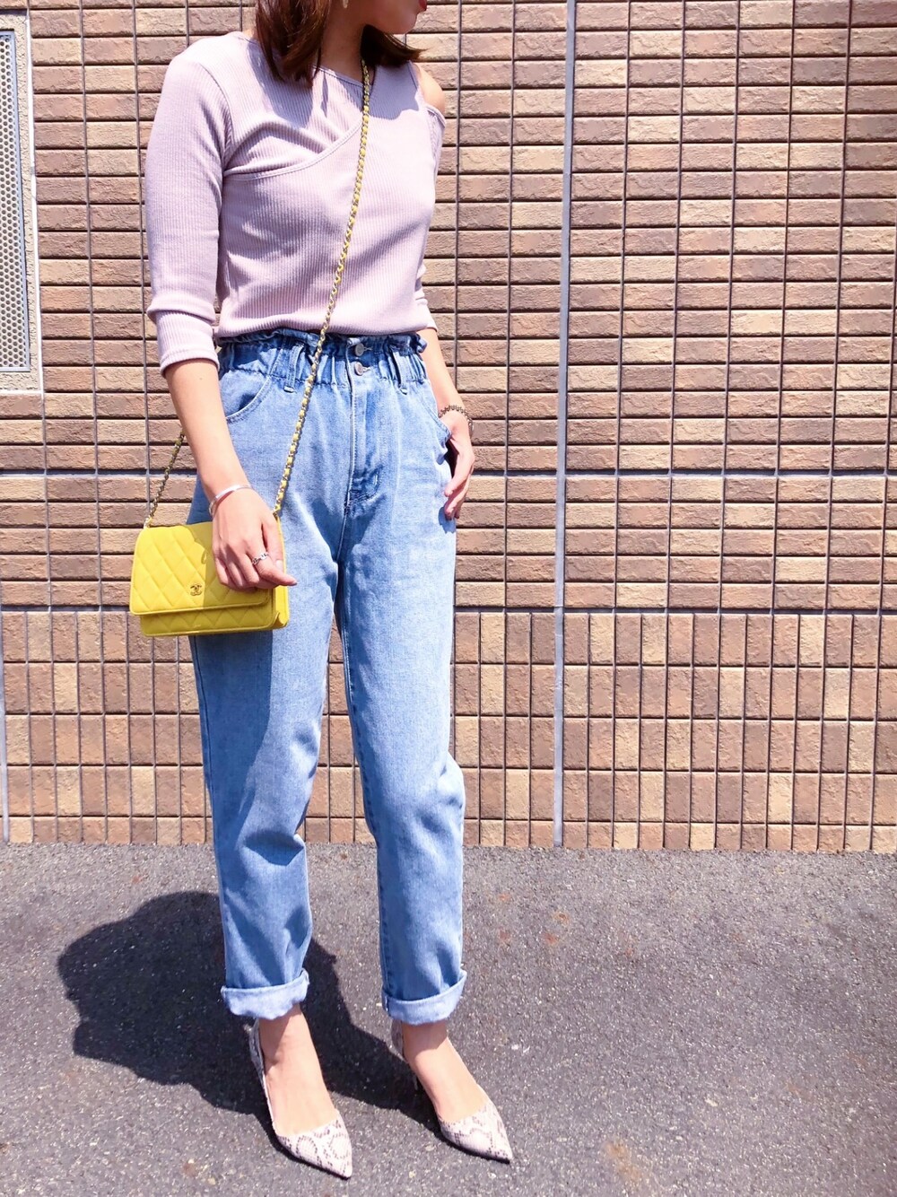 ブルー系のデニムパンツ、パープル系のTシャツ/カットソー、グレー系のパンプスを着用したレディースの春コーディネートの1枚目の写真