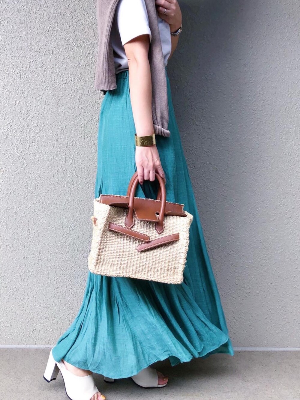 ベージュ系のかごバッグ、グリーン系のスカート、ベージュ系のTシャツ/カットソーを着用したレディースの夏コーディネートの1枚目の写真