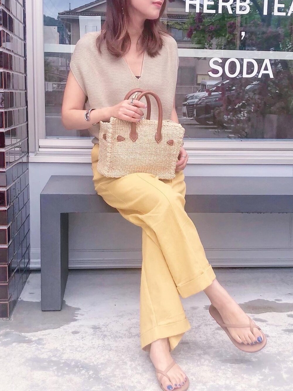 イエロー系のその他パンツ、ベージュ系のニット/セーター、ベージュ系のかごバッグを着用したレディースの夏コーディネートの1枚目の写真