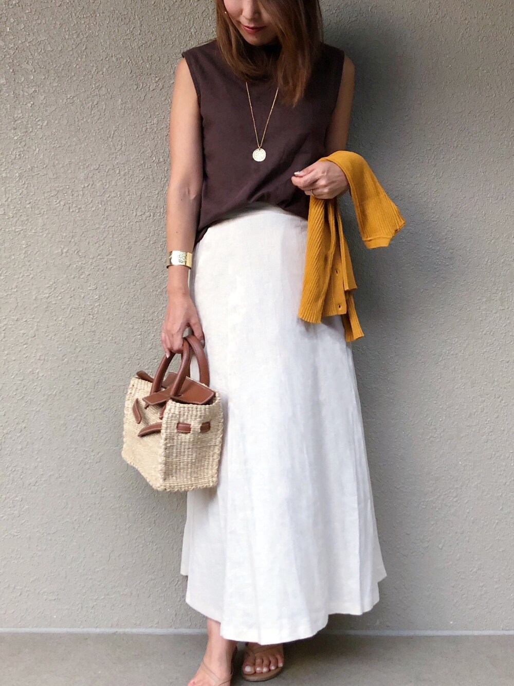 ベージュ系のスカート、ブラウン系のTシャツ/カットソー、イエロー系のカーディガン/ボレロを着用したレディースの夏コーディネートの1枚目の写真