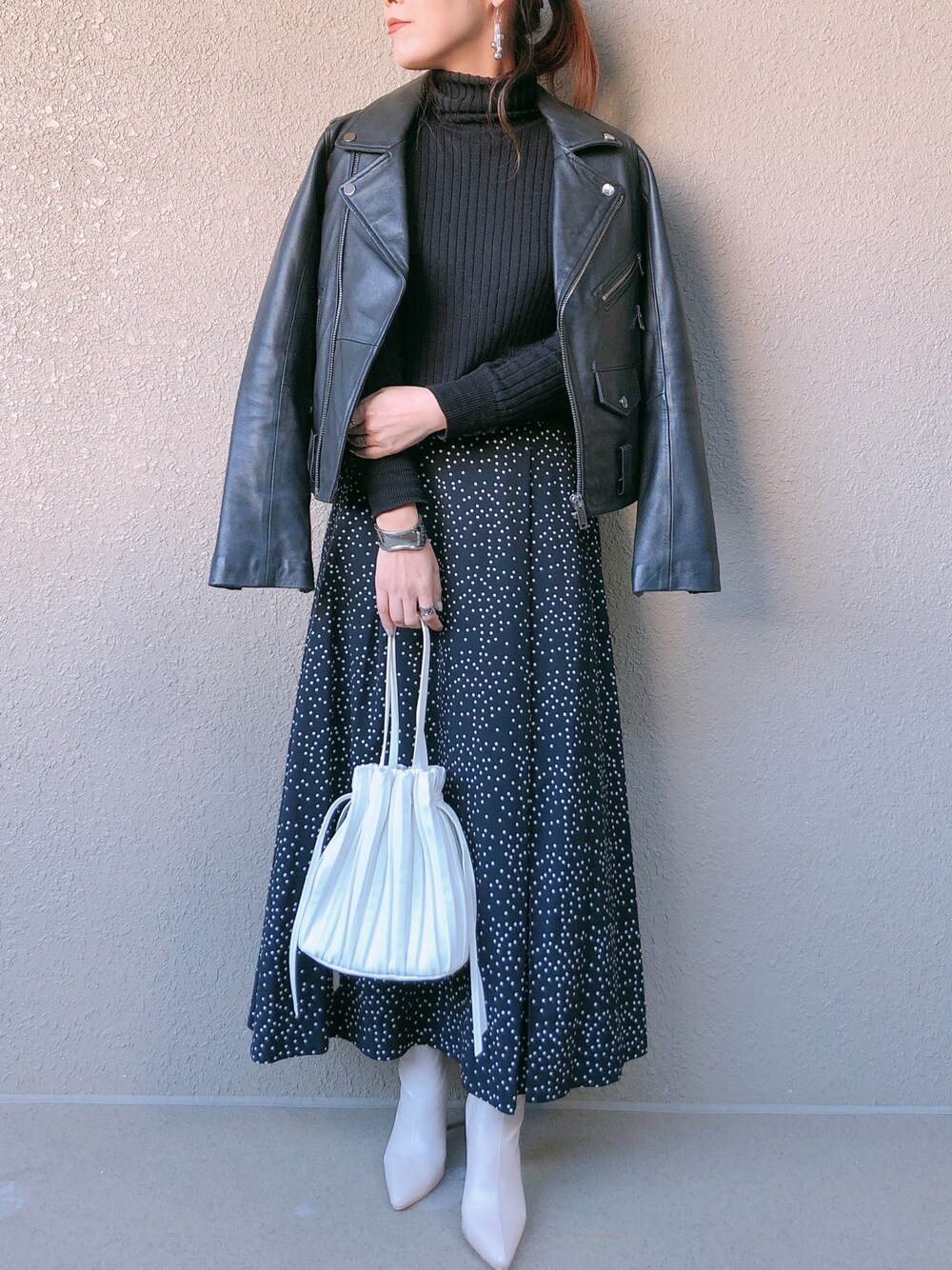 ブラック系のワンピース、ブラック系のライダースジャケット、ホワイト系のショルダーバッグを着用したレディースの春コーディネートの1枚目の写真