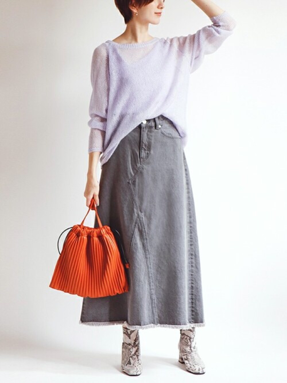 ブラック系のデニムスカート、パープル系のニット/セーター、オレンジ系のトートバッグを着用したレディースの秋コーディネートの1枚目の写真