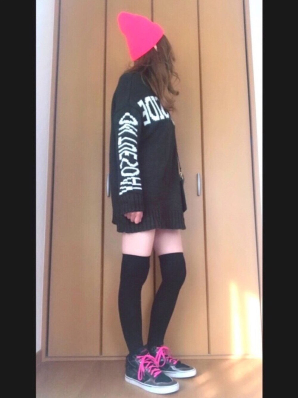 グリーン系のニット/セーター、ブラック系のスニーカー、ピンク系のニットキャップ/ビーニーを着用したレディースの秋コーディネートの1枚目の写真