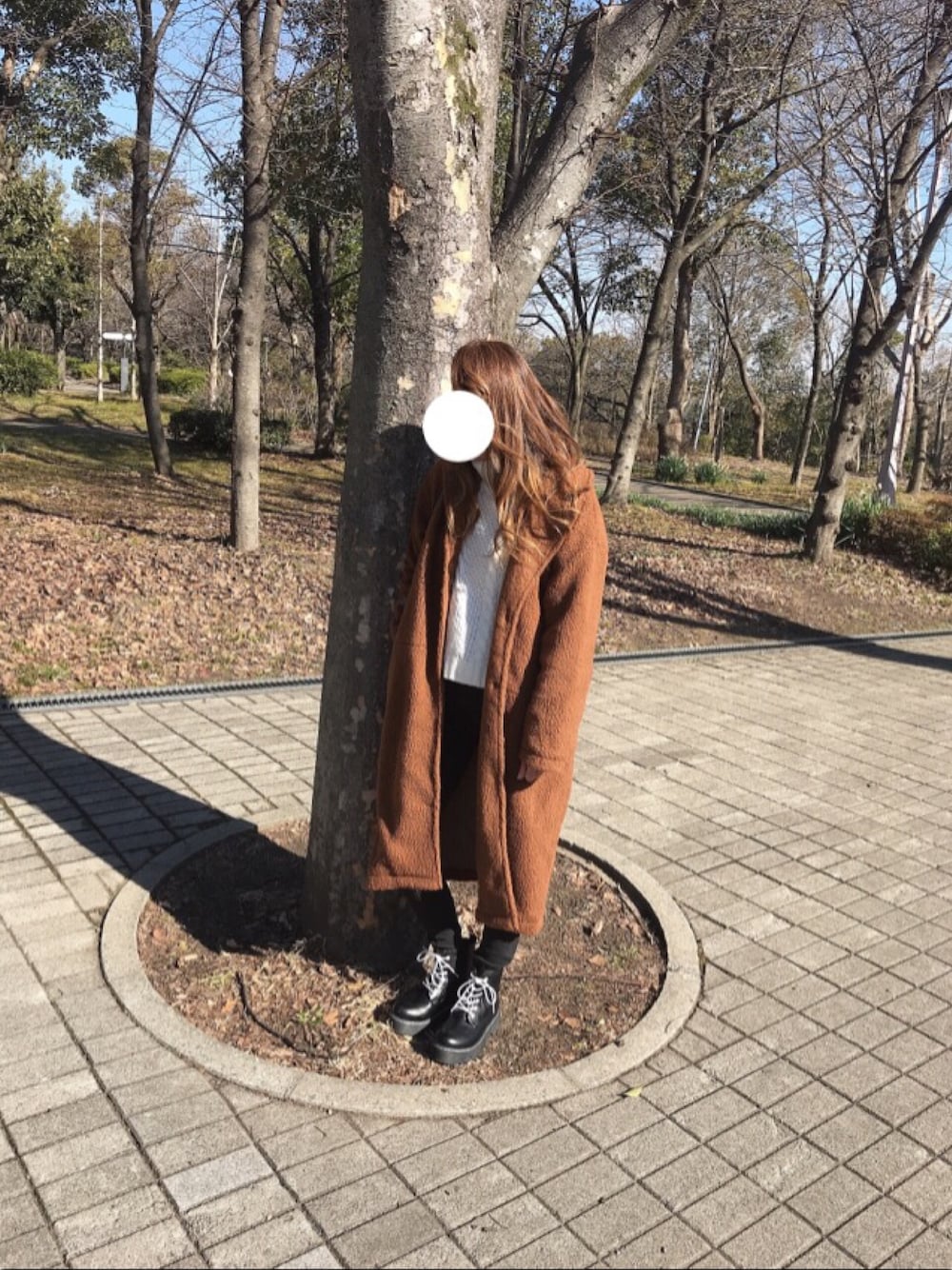 ブラウン系のチェスターコート、ホワイト系のニット/セーター、ブラック系のデニムパンツを着用したレディースの春コーディネートの1枚目の写真