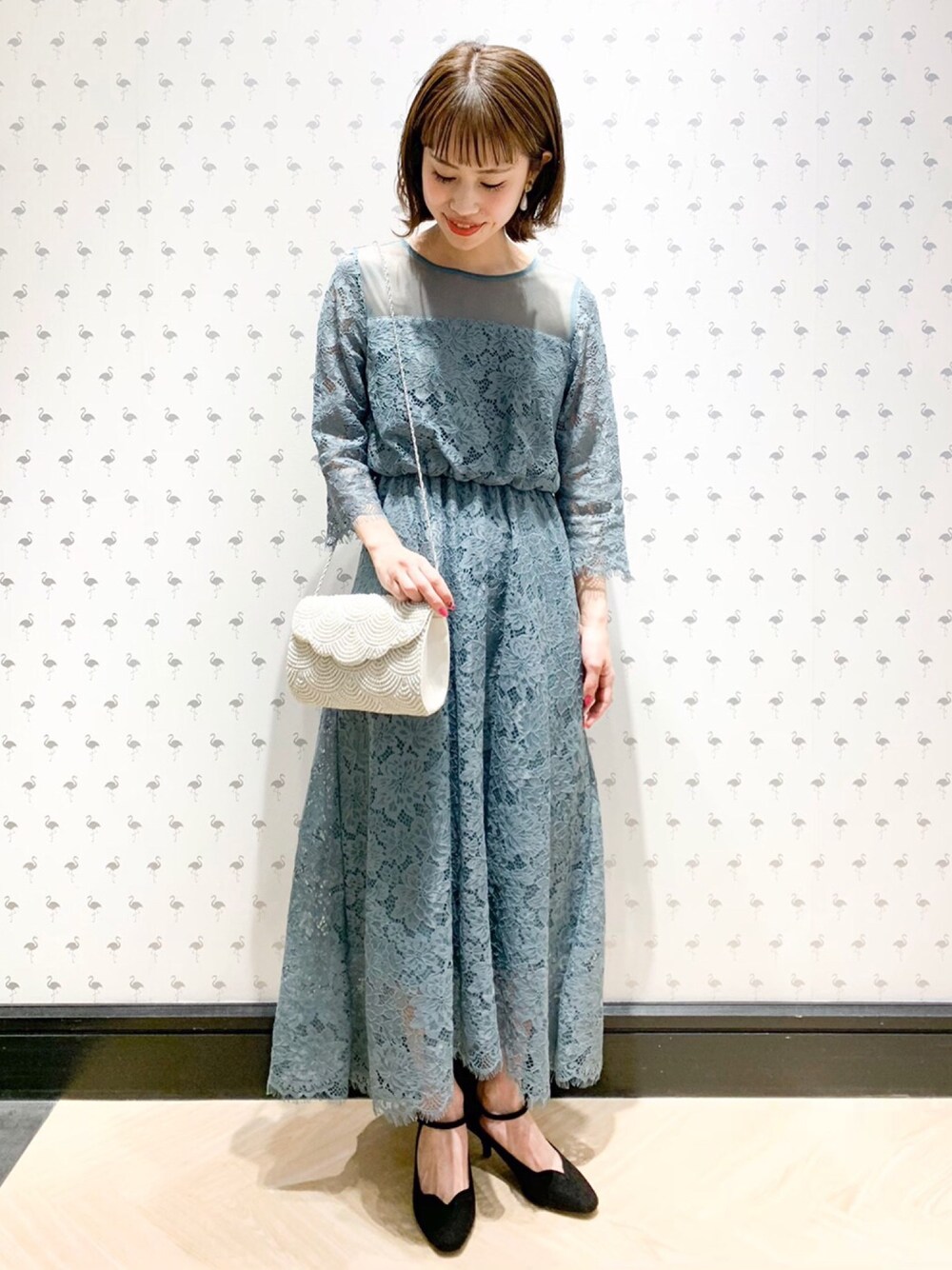 ブラック系のパンプス、ブルー系のドレス、ホワイト系のクラッチバッグを着用したレディースの春コーディネートの1枚目の写真