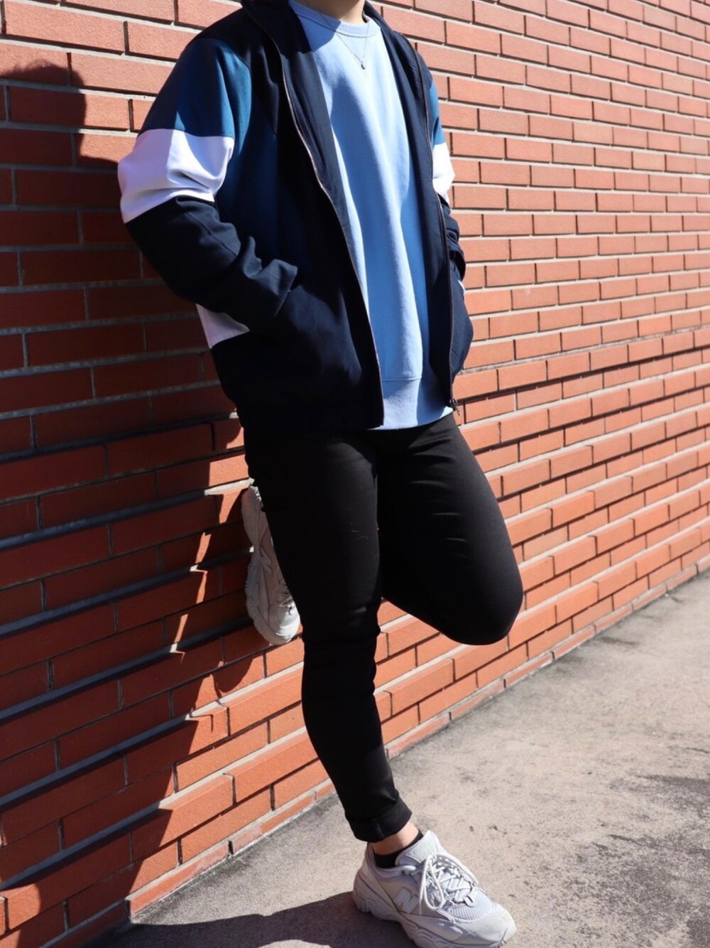 ブルー系のスウェット、ブラック系のデニムパンツ、ホワイト系のスニーカーを着用したメンズの秋コーディネートの1枚目の写真