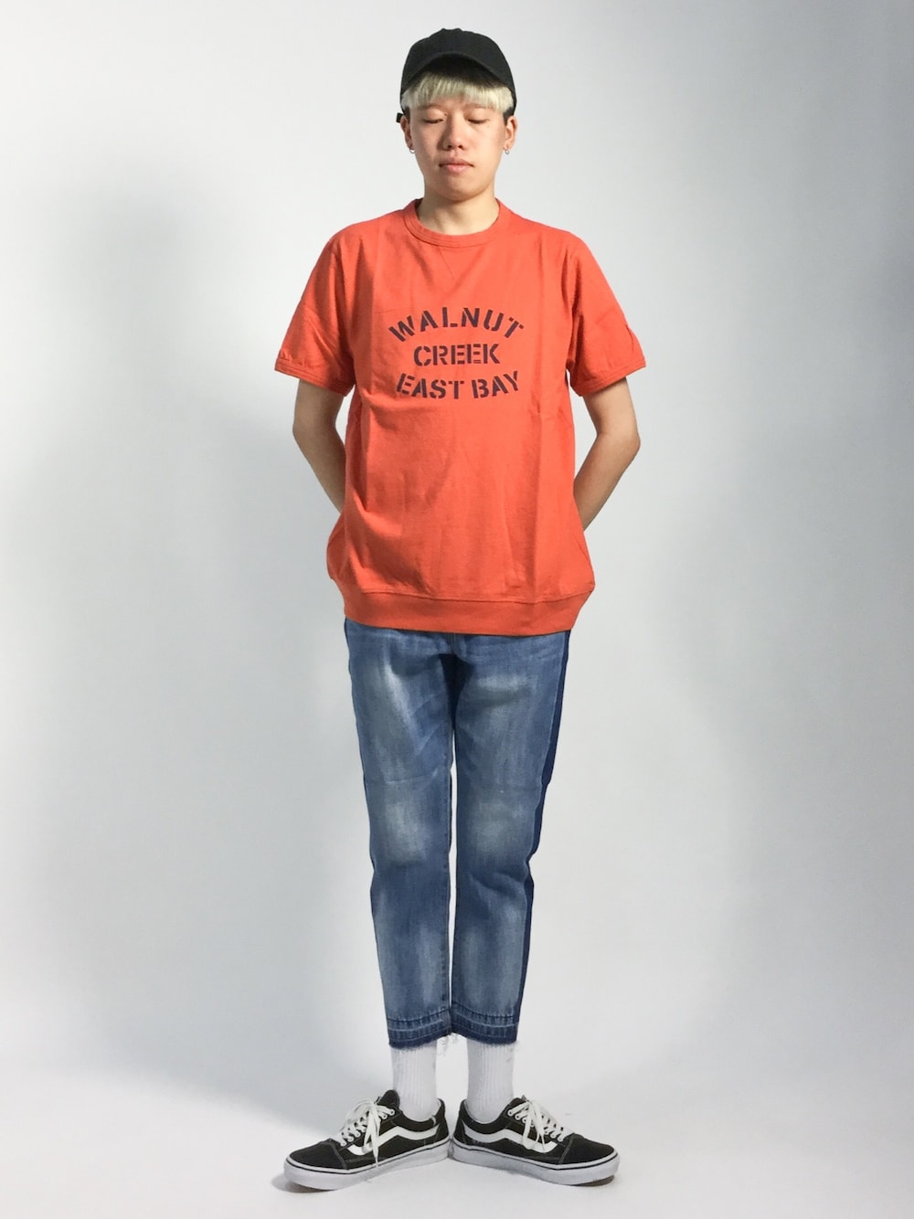 オレンジ系のTシャツ/カットソー、ブルー系のデニムパンツを着用したメンズの夏コーディネートの1枚目の写真