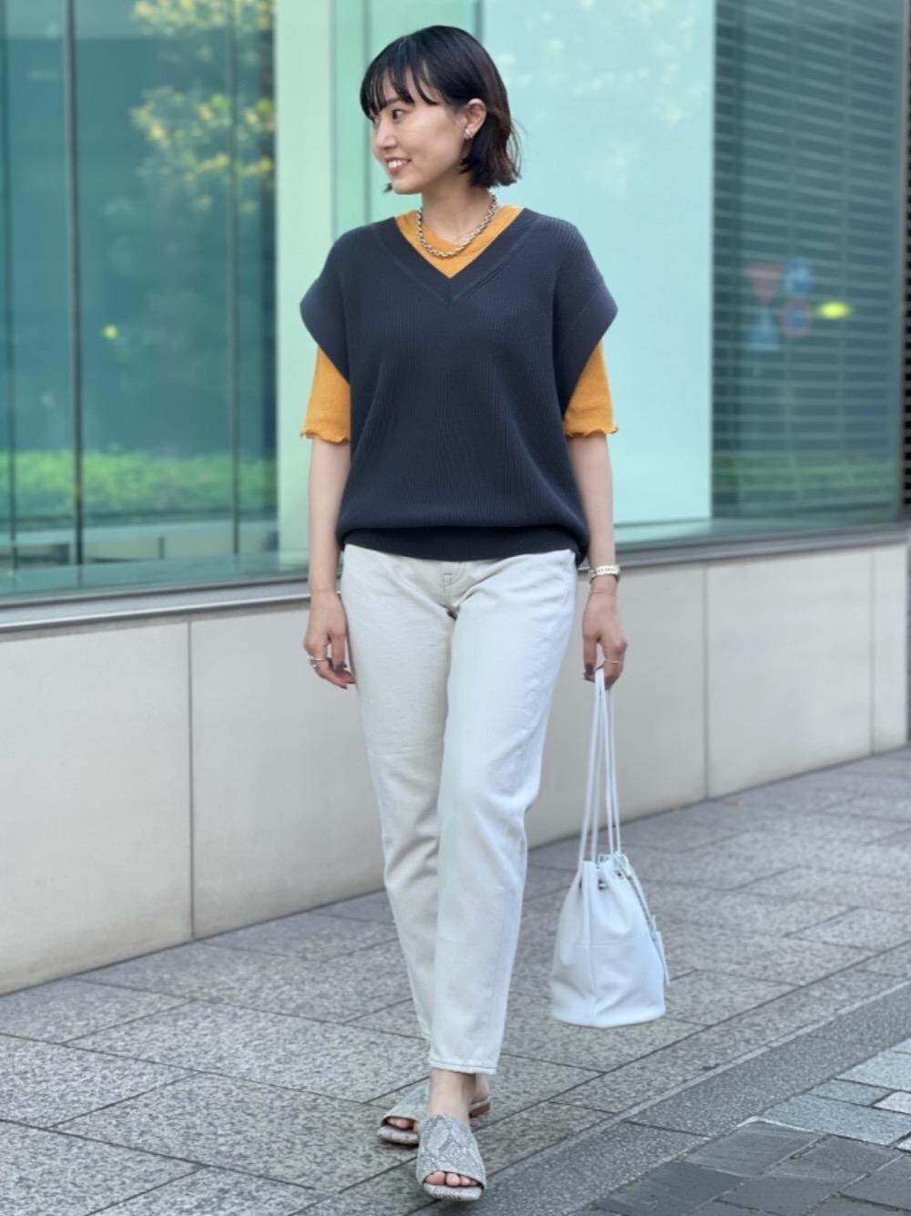 ホワイト系のデニムパンツ、グレー系のベスト、オレンジ系のTシャツ/カットソーを着用したレディースの春コーディネートの1枚目の写真