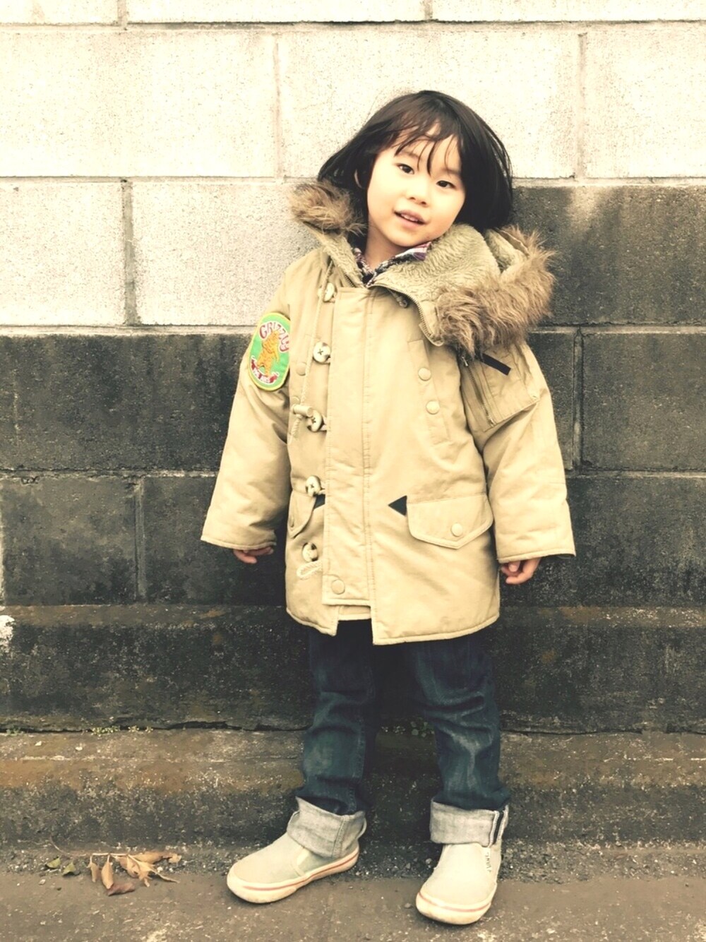 ベージュ系のミリタリージャケット、ブルー系のスリッポン、ブルー系のデニムパンツを着用したキッズの春コーディネートの1枚目の写真