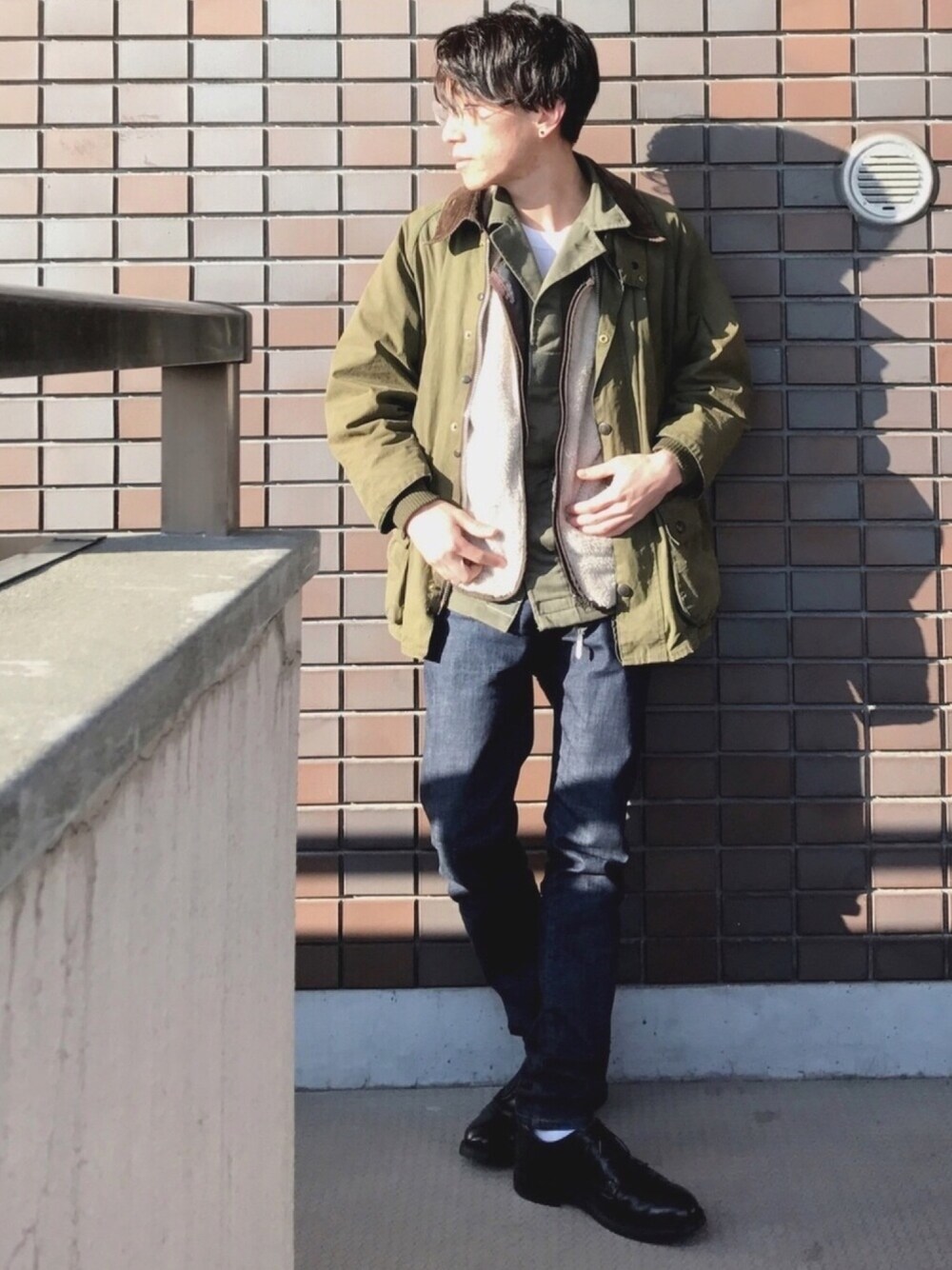 グリーン系のジャケット/アウター、ブラック系のベスト、ブルー系のデニムパンツを着用したメンズの春コーディネートの1枚目の写真