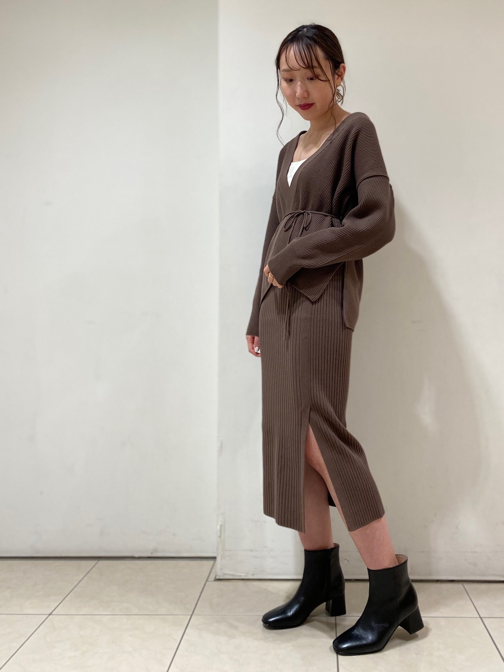 ブラウン系のカーディガン/ボレロ、ブラウン系のスカート、ブラック系のブーツを着用したレディースの秋コーディネートの1枚目の写真