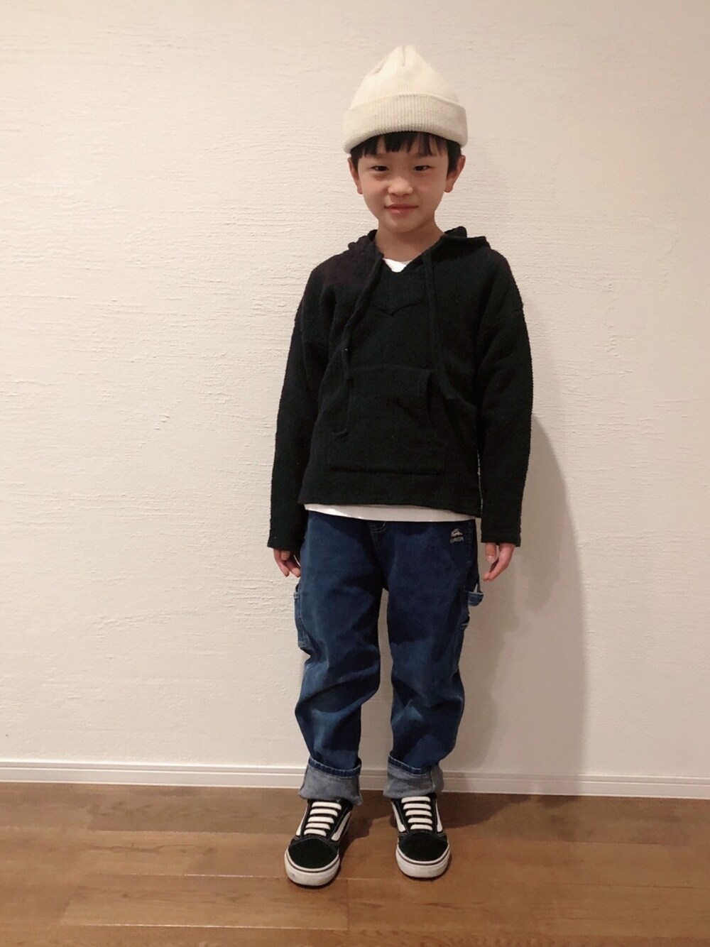 ブラック系のパーカー、ブラック系のスニーカー、ベージュ系のニットキャップ/ビーニーを着用したキッズの冬コーディネートの1枚目の写真
