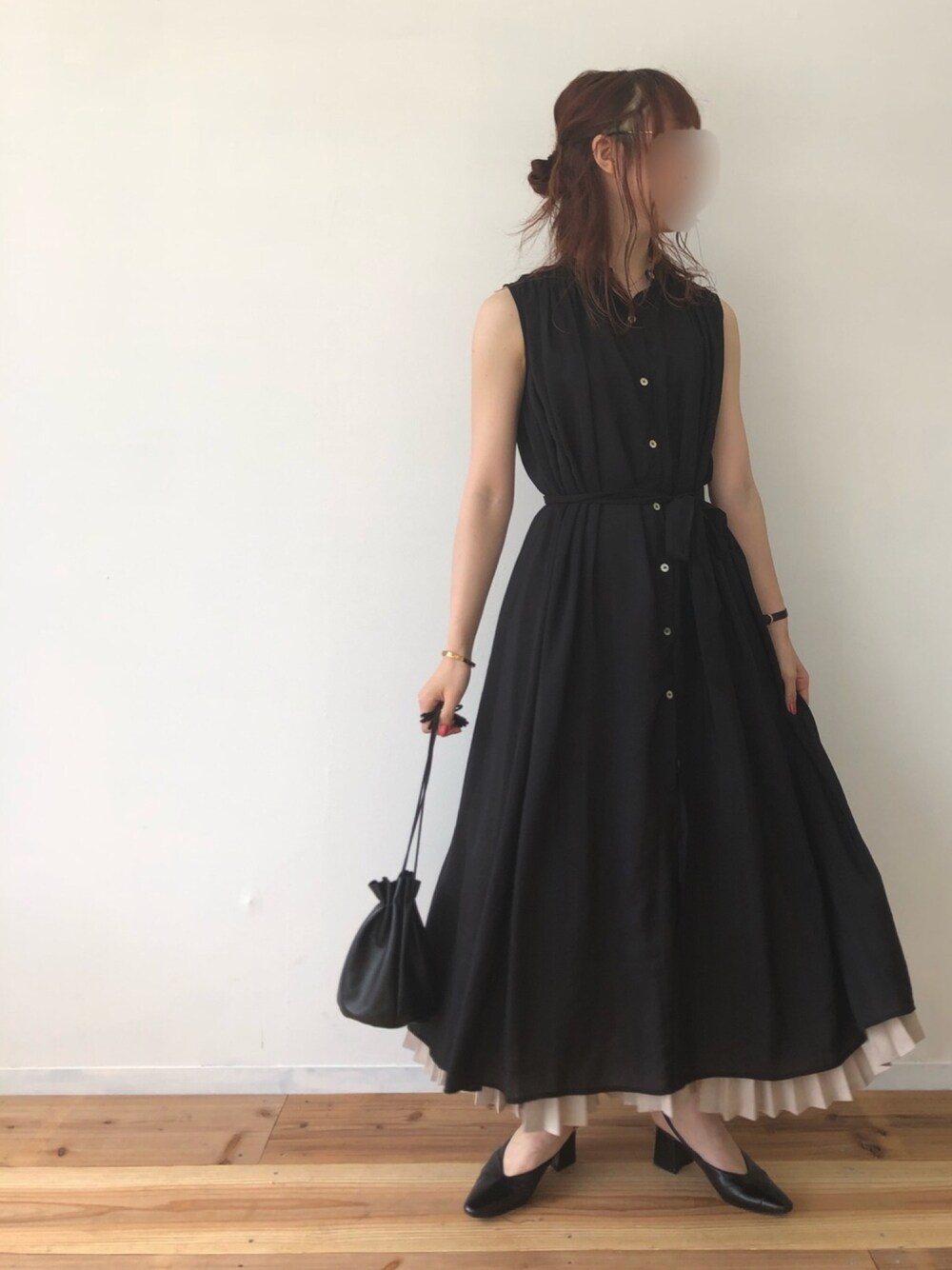 ブラック系のシャツワンピース、ベージュ系のスカートを着用したレディースの夏コーディネートの1枚目の写真