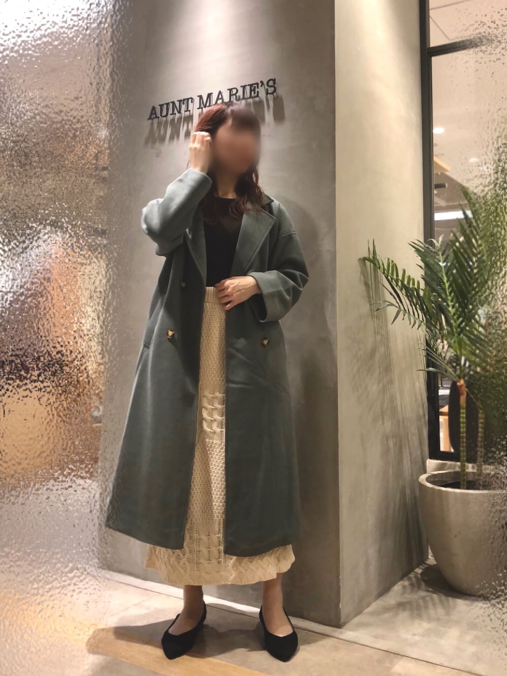 ベージュ系のスカート、グリーン系のチェスターコートを着用したレディースの秋コーディネートの1枚目の写真