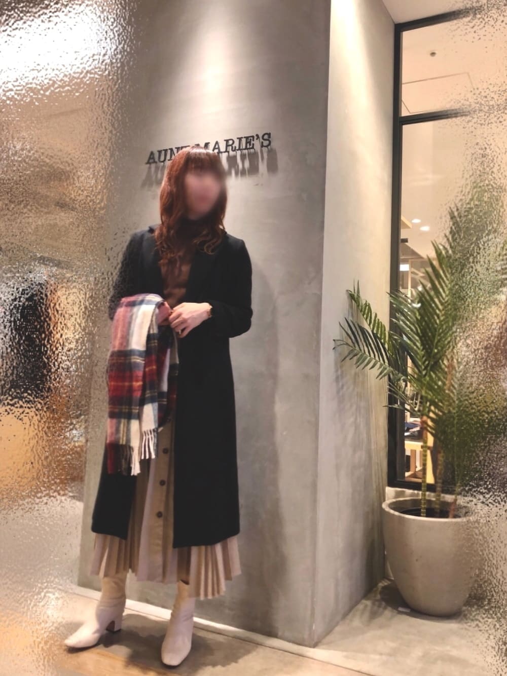 ホワイト系のブーツ、ベージュ系のスカート、ブラック系のチェスターコートを着用したレディースの冬コーディネートの1枚目の写真