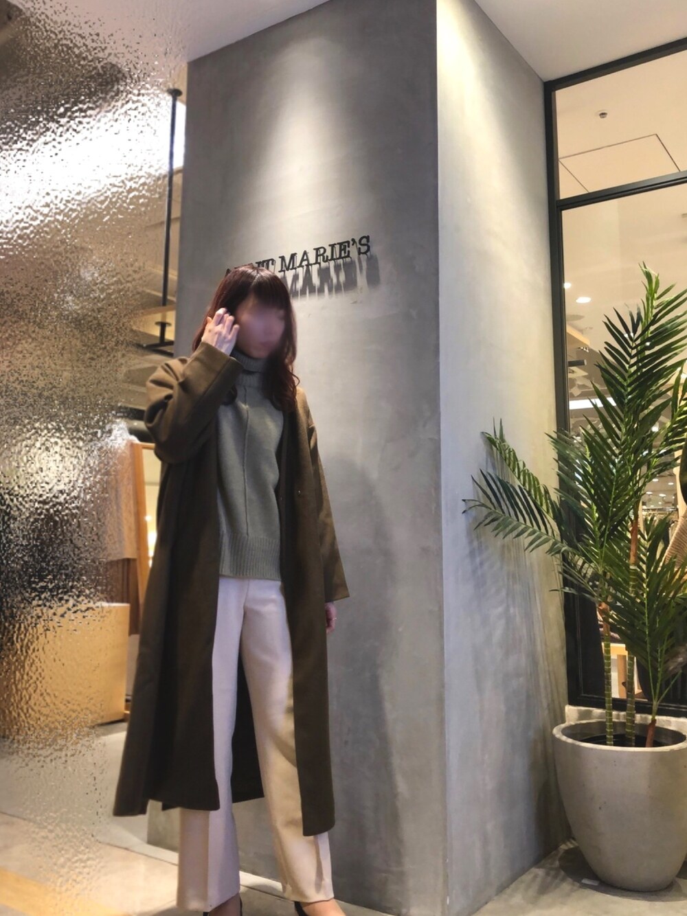 ブラウン系のノーカラーコート、グリーン系のニット/セーターを着用したレディースの冬コーディネートの1枚目の写真