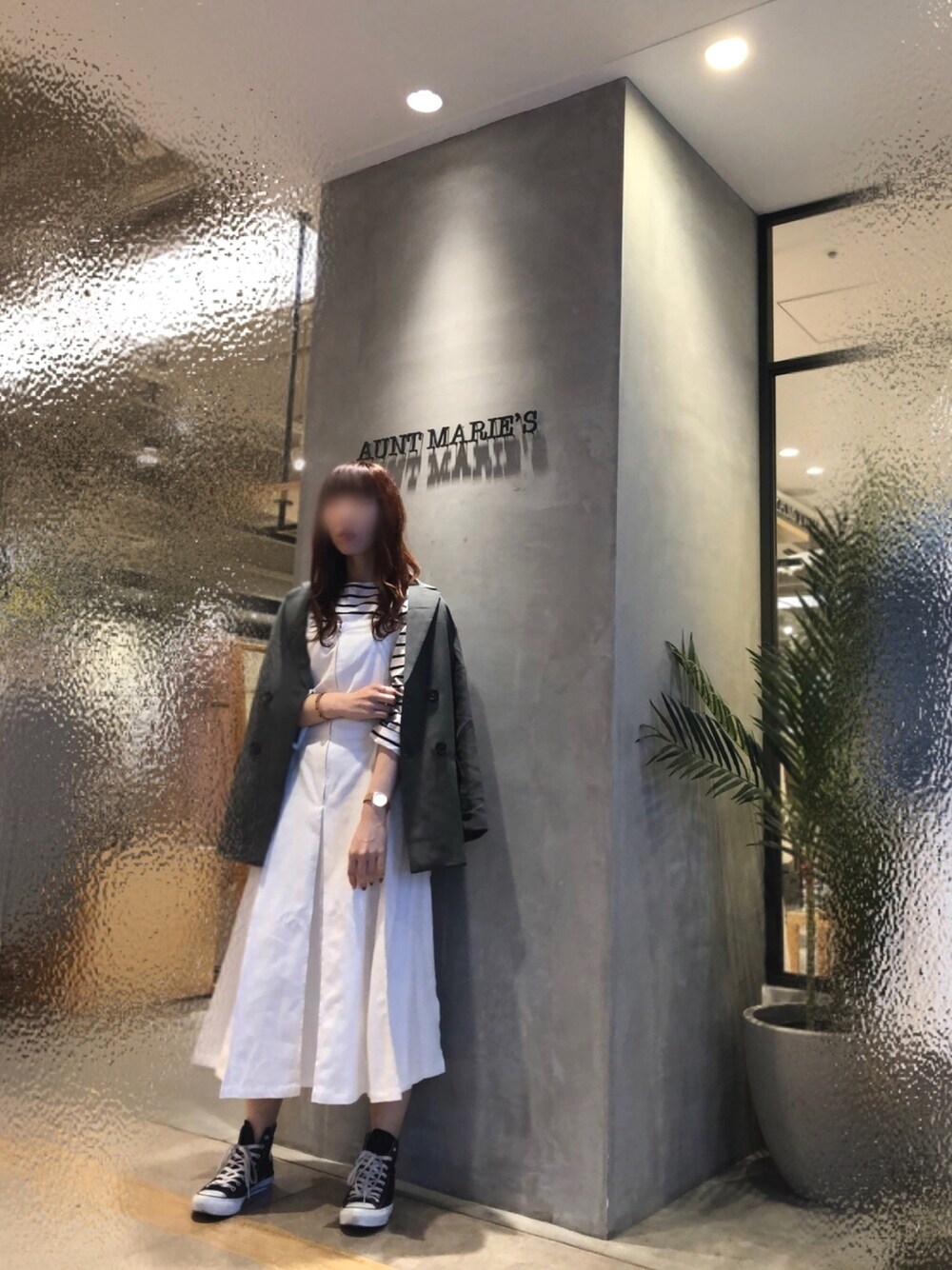 グリーン系のテーラードジャケット、ブラック系のTシャツ/カットソー、ホワイト系のジャンパースカートを着用したレディースの春コーディネートの1枚目の写真