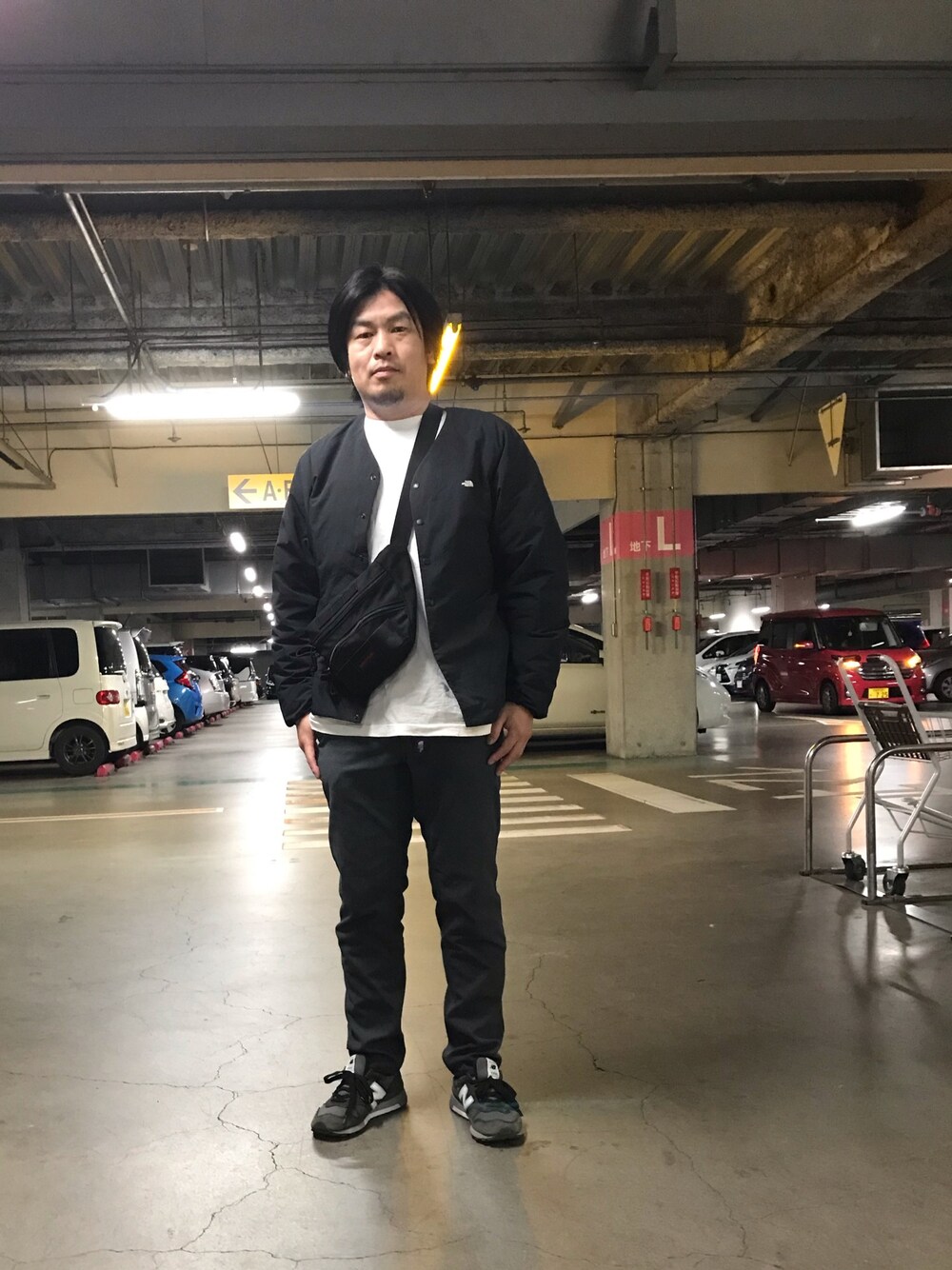ブラック系のダウンジャケット/コート、ホワイト系のTシャツ/カットソー、グレー系のチノパンツを着用したメンズの冬コーディネートの1枚目の写真
