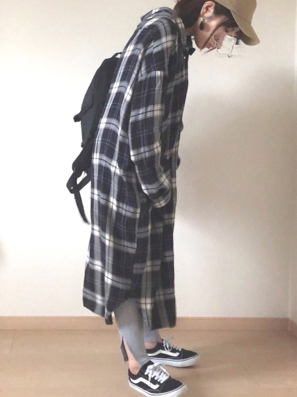 ブラック系のシャツワンピース、ブラック系のバックパック/リュック、ブラック系のスニーカーを着用したレディースの秋コーディネートの1枚目の写真