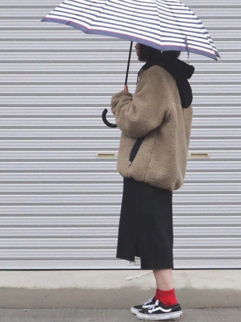 ベージュ系のブルゾン、ブラック系のスニーカー、ホワイト系の長傘を着用したレディースの冬コーディネートの1枚目の写真