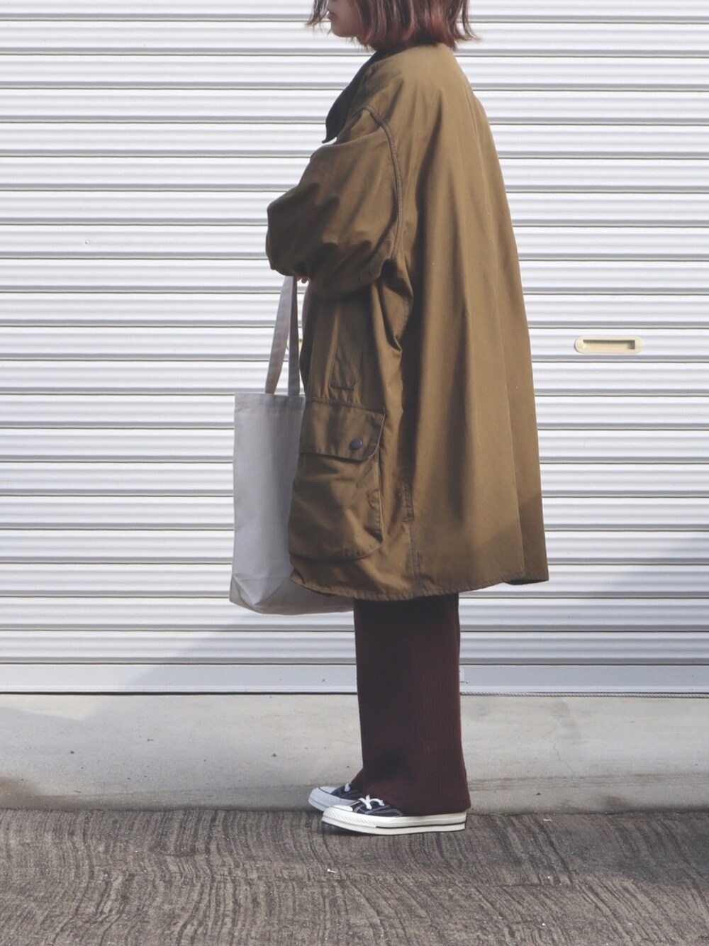 ブラック系のスニーカー、ホワイト系のトートバッグを着用したレディースの冬コーディネートの1枚目の写真