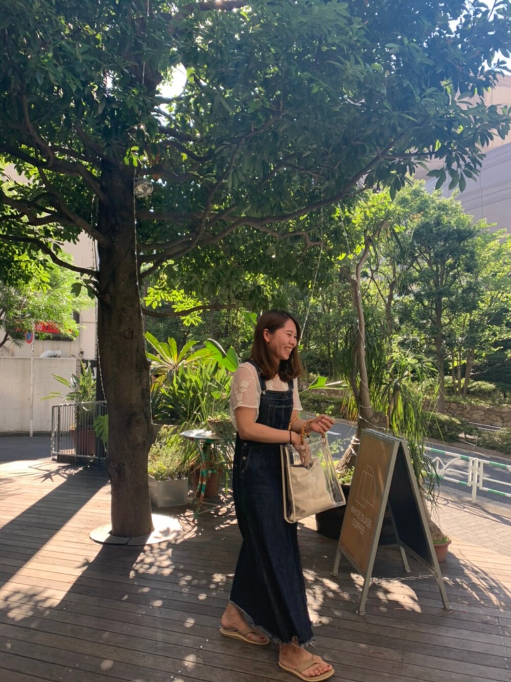 ブルー系のオールインワン・サロペット、ブラウン系のサンダル、ホワイト系のトップスを着用したレディースの夏コーディネートの1枚目の写真