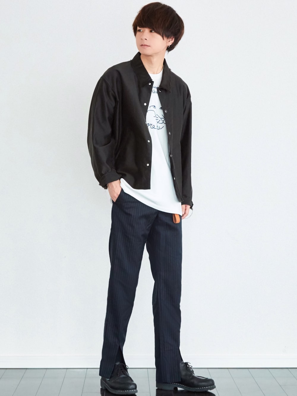 ブラック系のブルゾン、ホワイト系のTシャツ/カットソー、ブルー系のスラックスを着用したメンズの春コーディネートの1枚目の写真