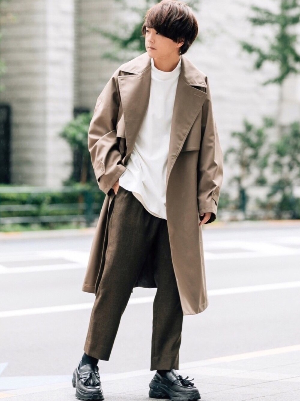 ブラウン系のトレンチコート、ホワイト系のTシャツ/カットソー、ベージュ系のタンクトップを着用したメンズの秋コーディネートの1枚目の写真