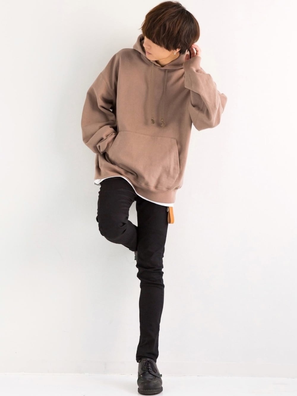 ブラウン系のパーカー、ホワイト系のタンクトップ、ブラック系のデニムパンツを着用したメンズの冬コーディネートの1枚目の写真