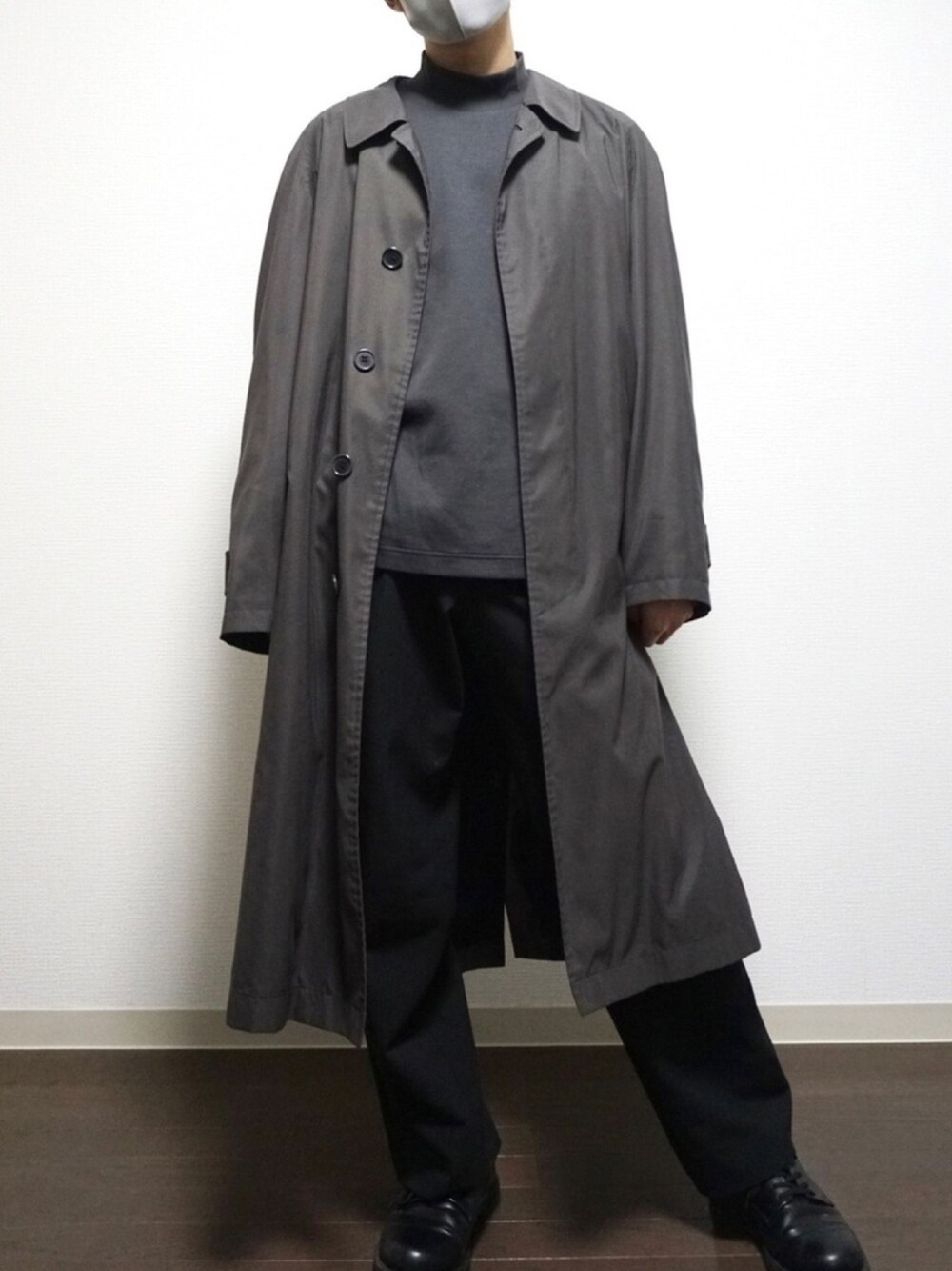 グレー系のトップス、ブラック系のスラックス、ブラック系のドレスシューズを着用したメンズの冬コーディネートの1枚目の写真