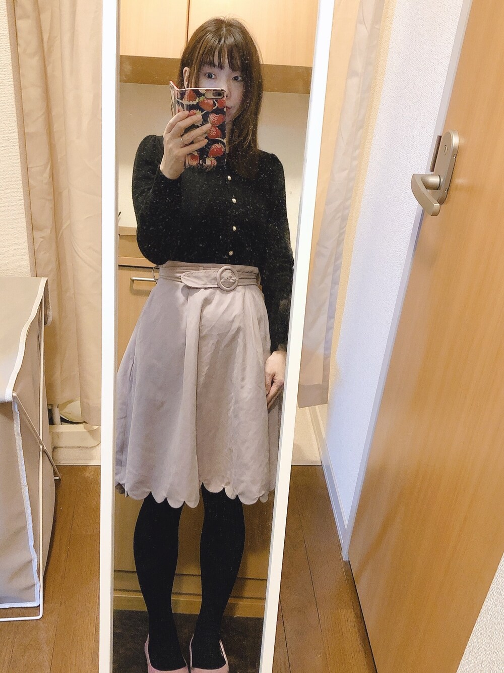 ブラック系のカーディガン/ボレロ、ピンク系のスカート、ピンク系のパンプスを着用したレディースの秋コーディネートの1枚目の写真