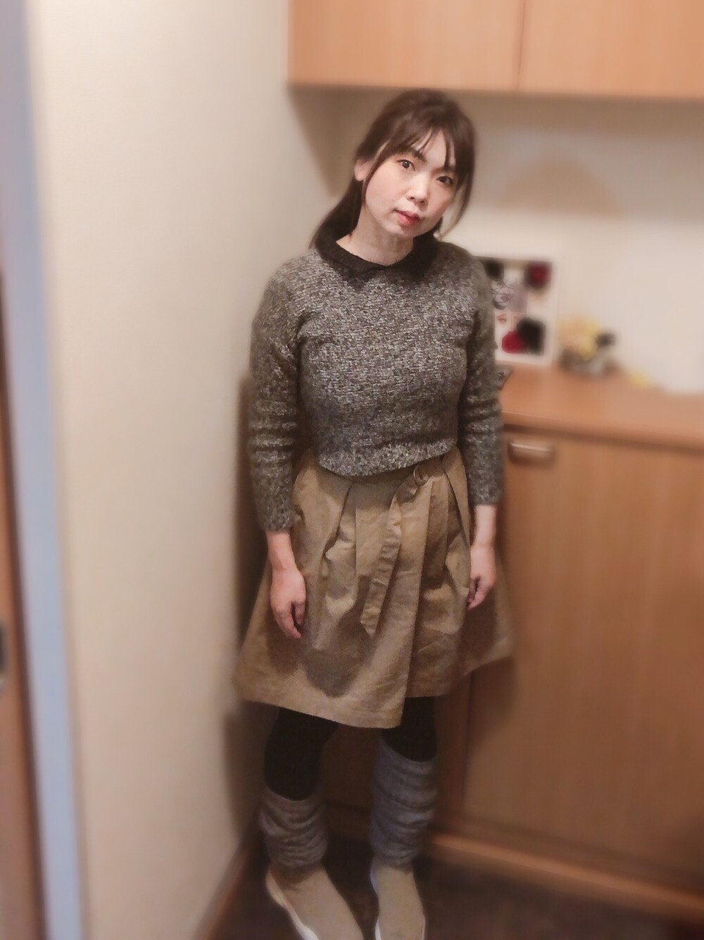 グレー系のニット/セーター、ベージュ系のスカート、ベージュ系のスニーカーを着用したレディースの冬コーディネートの1枚目の写真