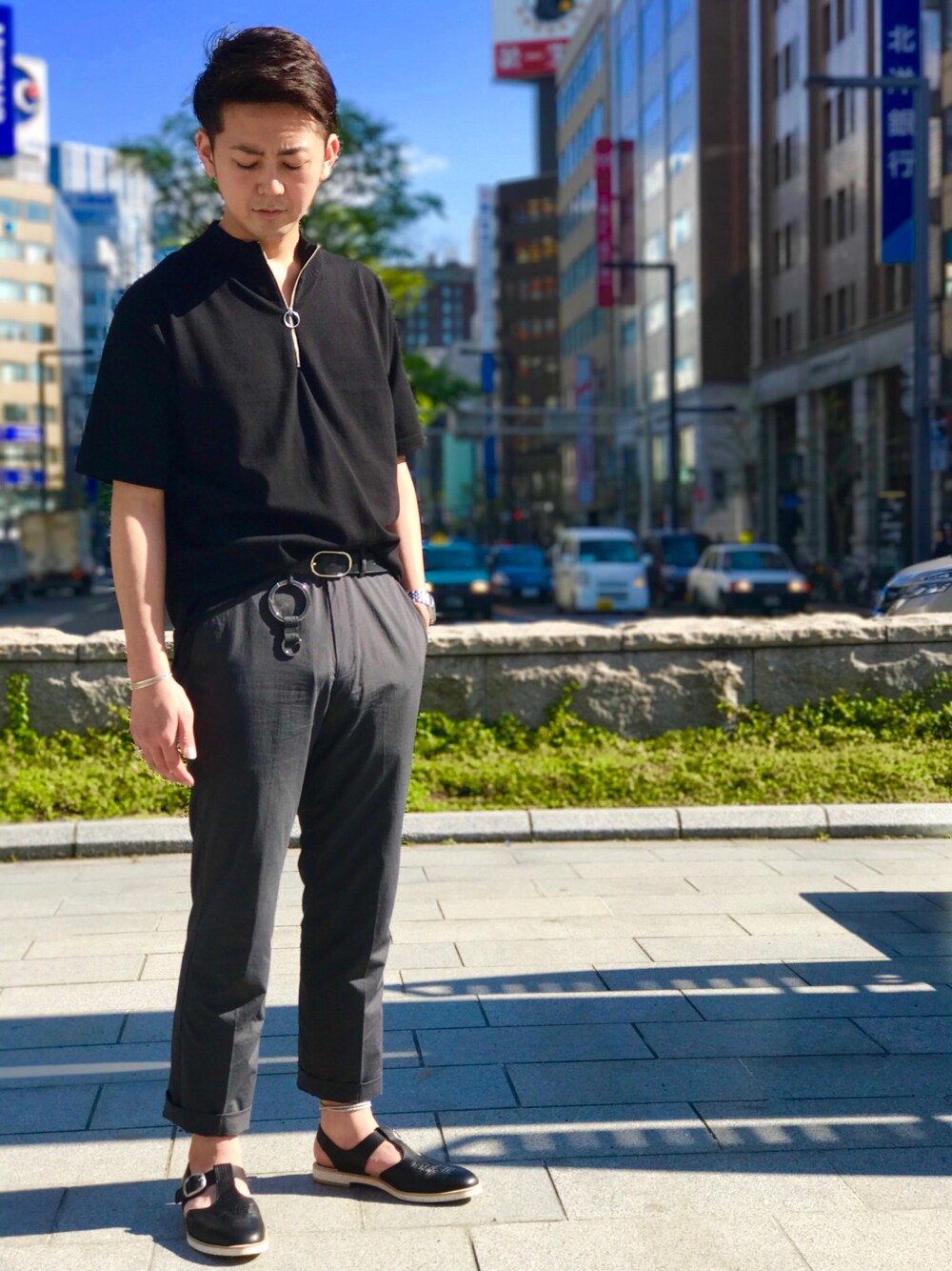 ブラック系のニット/セーター、ブラック系のサンダル、グレー系のスラックスを着用したメンズの春コーディネートの1枚目の写真
