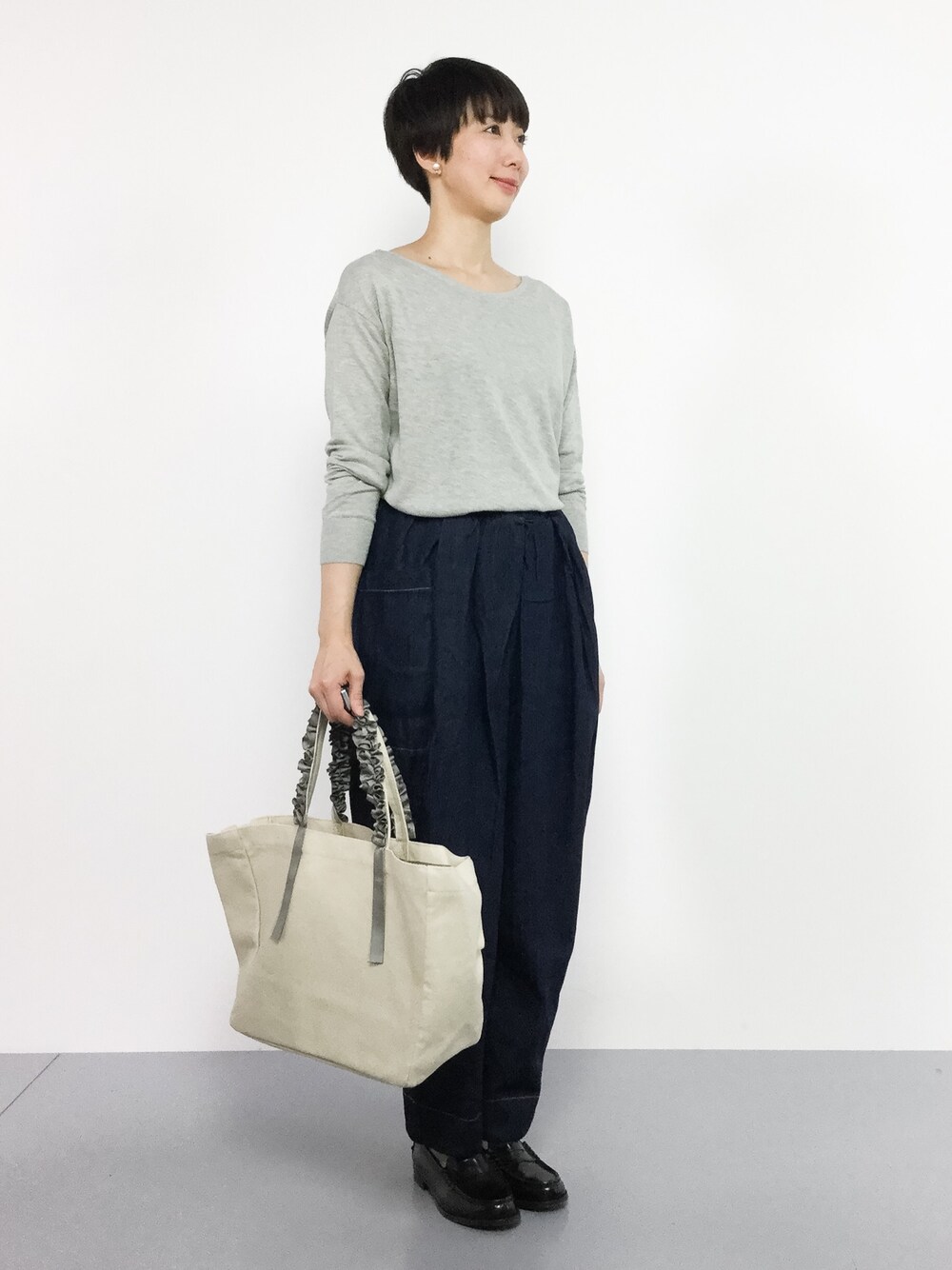 ブルー系のデニムパンツ、グレー系のニット/セーター、ホワイト系のトートバッグを着用したレディースの夏コーディネートの1枚目の写真