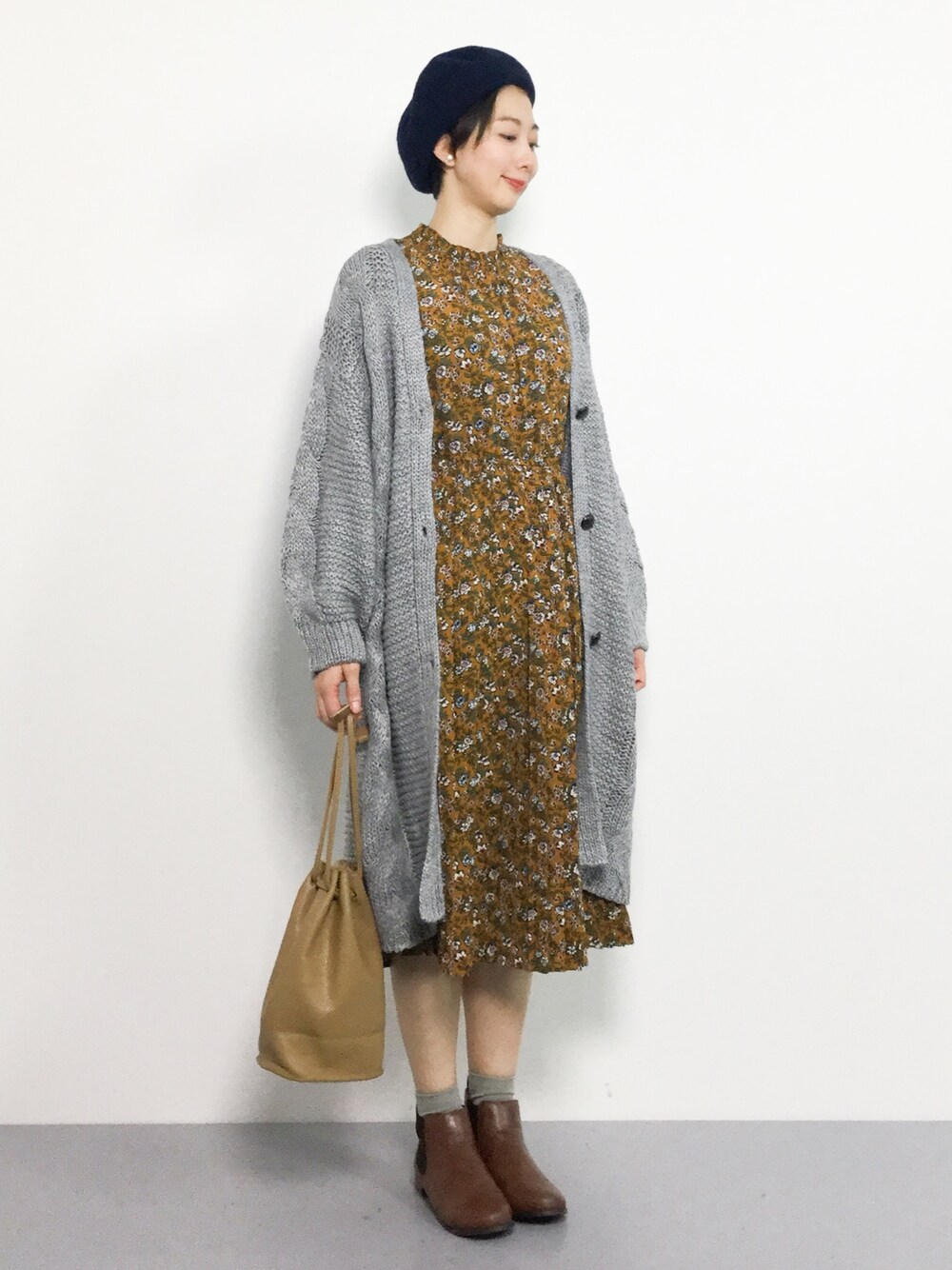 イエロー系のワンピース、グレー系のカーディガン/ボレロを着用したレディースの秋コーディネートの1枚目の写真