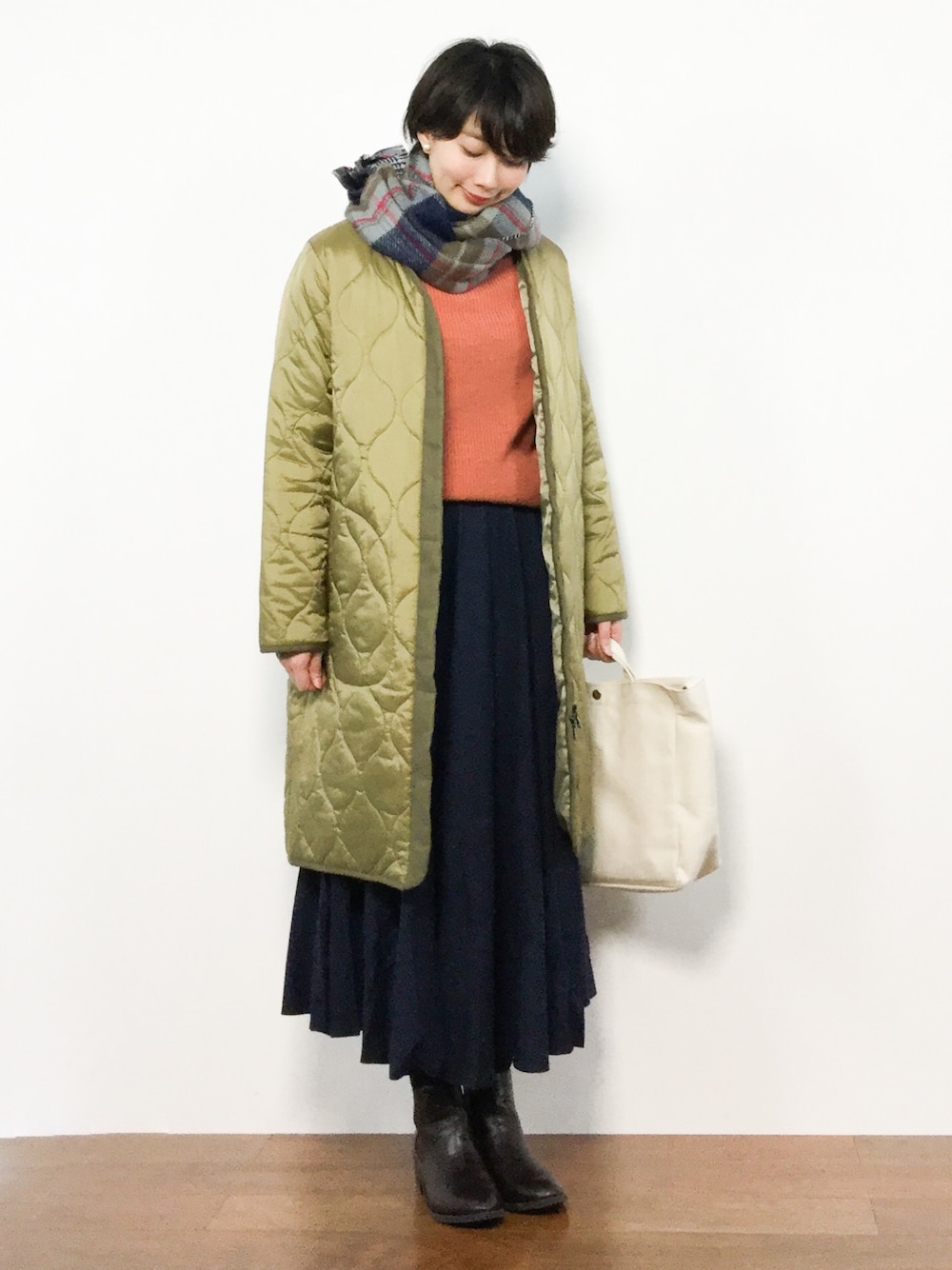 ブルー系のスカート、オレンジ系のニット/セーター、グリーン系のノーカラージャケットを着用したレディースの冬コーディネートの1枚目の写真