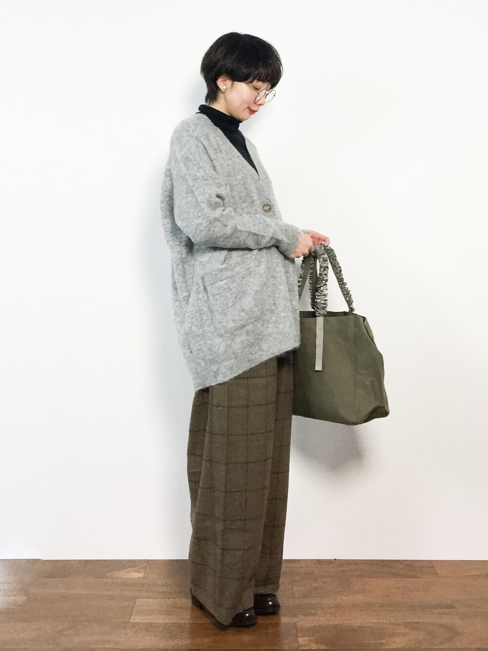 グリーン系のトートバッグ、ブラウン系のその他パンツ、グレー系のカーディガン/ボレロを着用したレディースの冬コーディネートの1枚目の写真