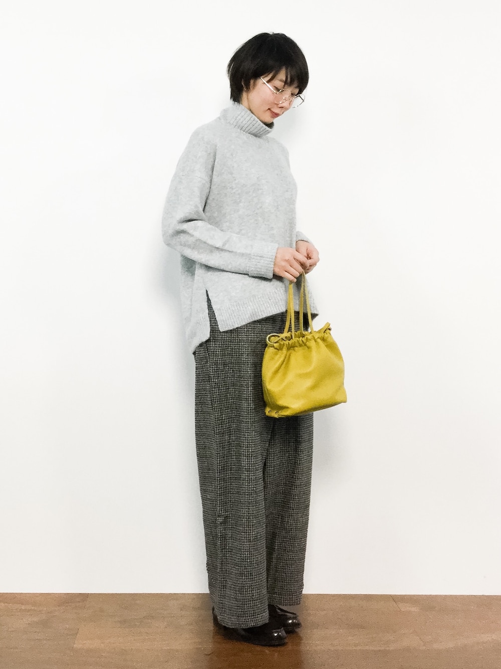 イエロー系のハンドバッグ、グレー系のニット/セーター、グレー系のその他パンツを着用したレディースの冬コーディネートの1枚目の写真