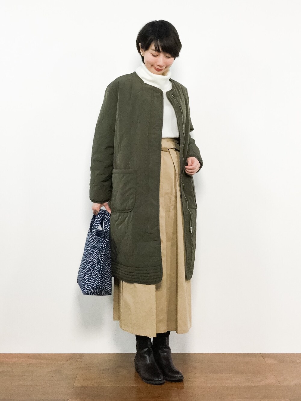 ブルー系のトートバッグ、グリーン系のその他アウター、ベージュ系のスカートを着用したレディースの冬コーディネートの1枚目の写真