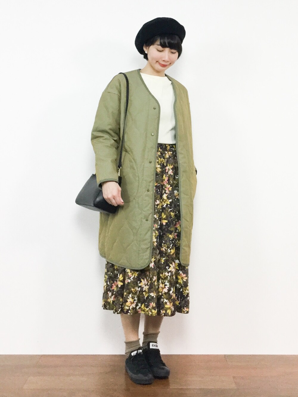 グリーン系のその他アウター、イエロー系のスカート、ホワイト系のニット/セーターを着用したレディースの冬コーディネートの1枚目の写真