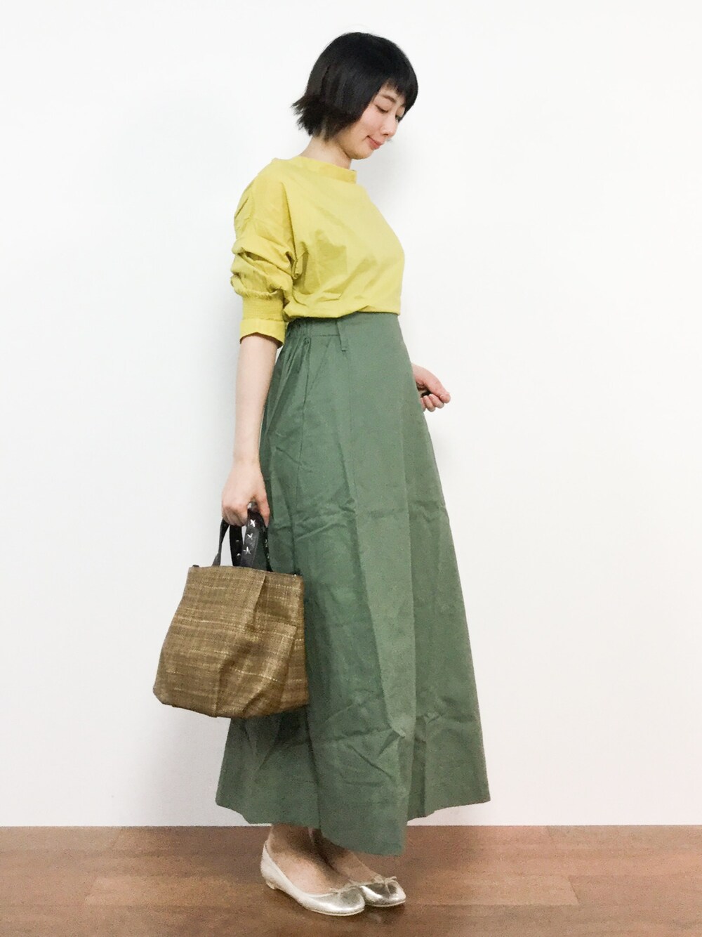 グリーン系のスカート、イエロー系のシャツ/ブラウス、ブラウン系のトートバッグを着用したレディースの春コーディネートの1枚目の写真
