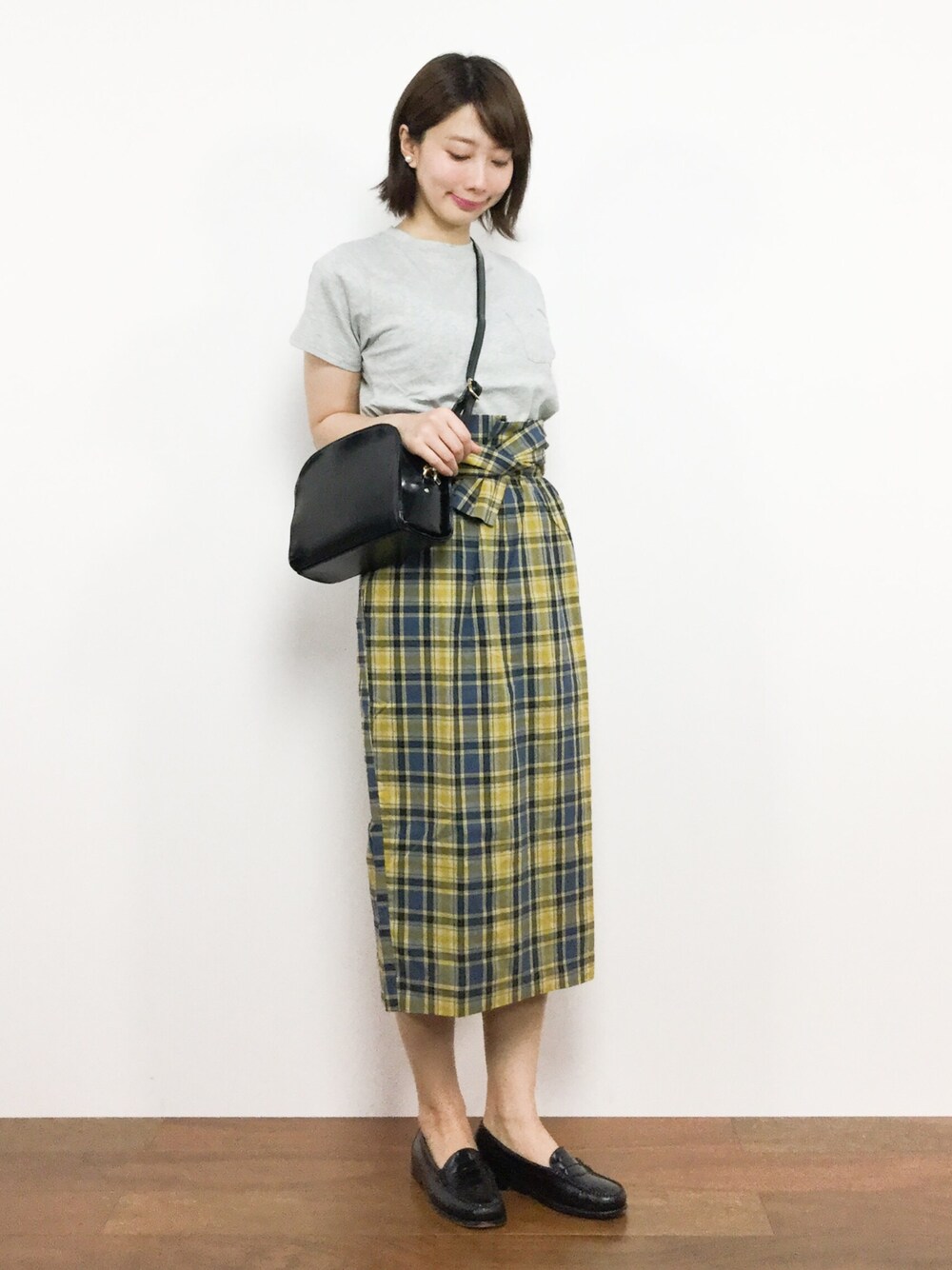 イエロー系のスカート、グレー系のTシャツ/カットソー、ブラック系のショルダーバッグを着用したレディースの夏コーディネートの1枚目の写真
