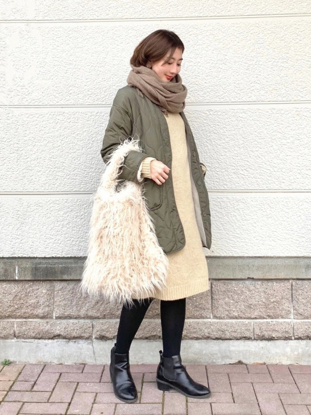 ベージュ系のワンピース、グリーン系のブルゾン、ホワイト系のショルダーバッグを着用したレディースの冬コーディネートの1枚目の写真