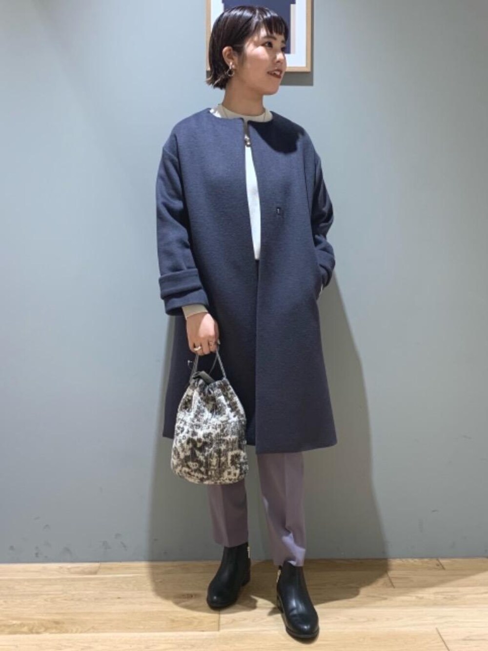 グレー系のノーカラーコート、パープル系のその他パンツ、ブラック系のブーツを着用したレディースの冬コーディネートの1枚目の写真