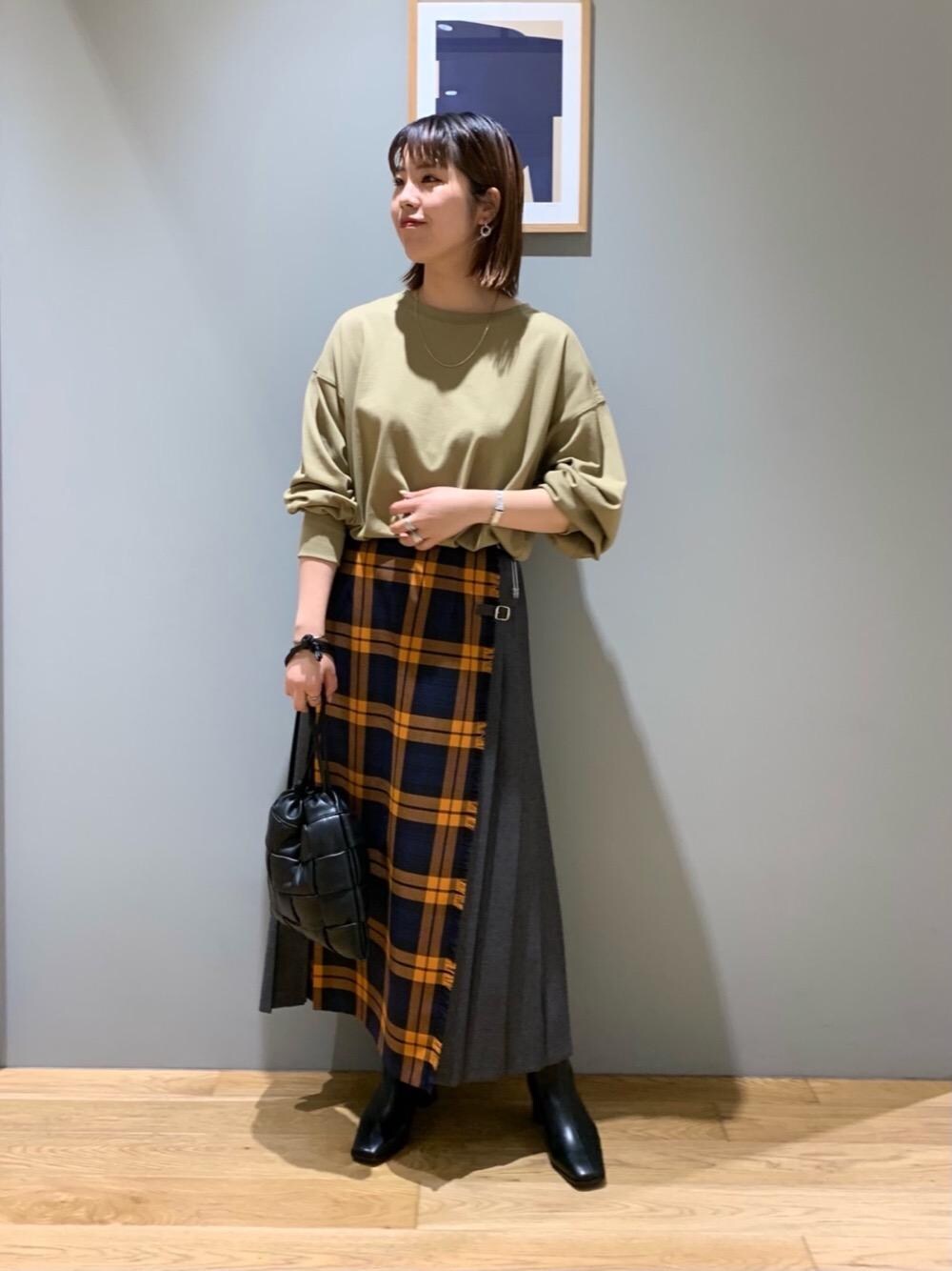 ブラック系のショルダーバッグ、オレンジ系のスカート、ベージュ系のTシャツ/カットソーを着用したレディースの秋コーディネートの1枚目の写真