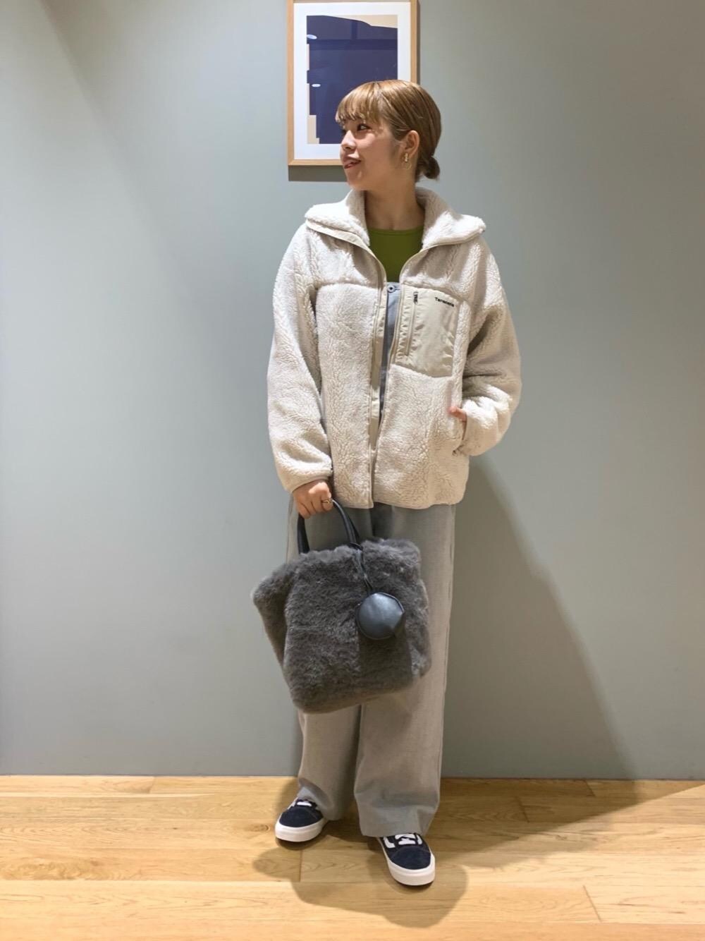 グリーン系のニット/セーター、グレー系のトートバッグ、ブルー系のスニーカーを着用したレディースの秋コーディネートの1枚目の写真