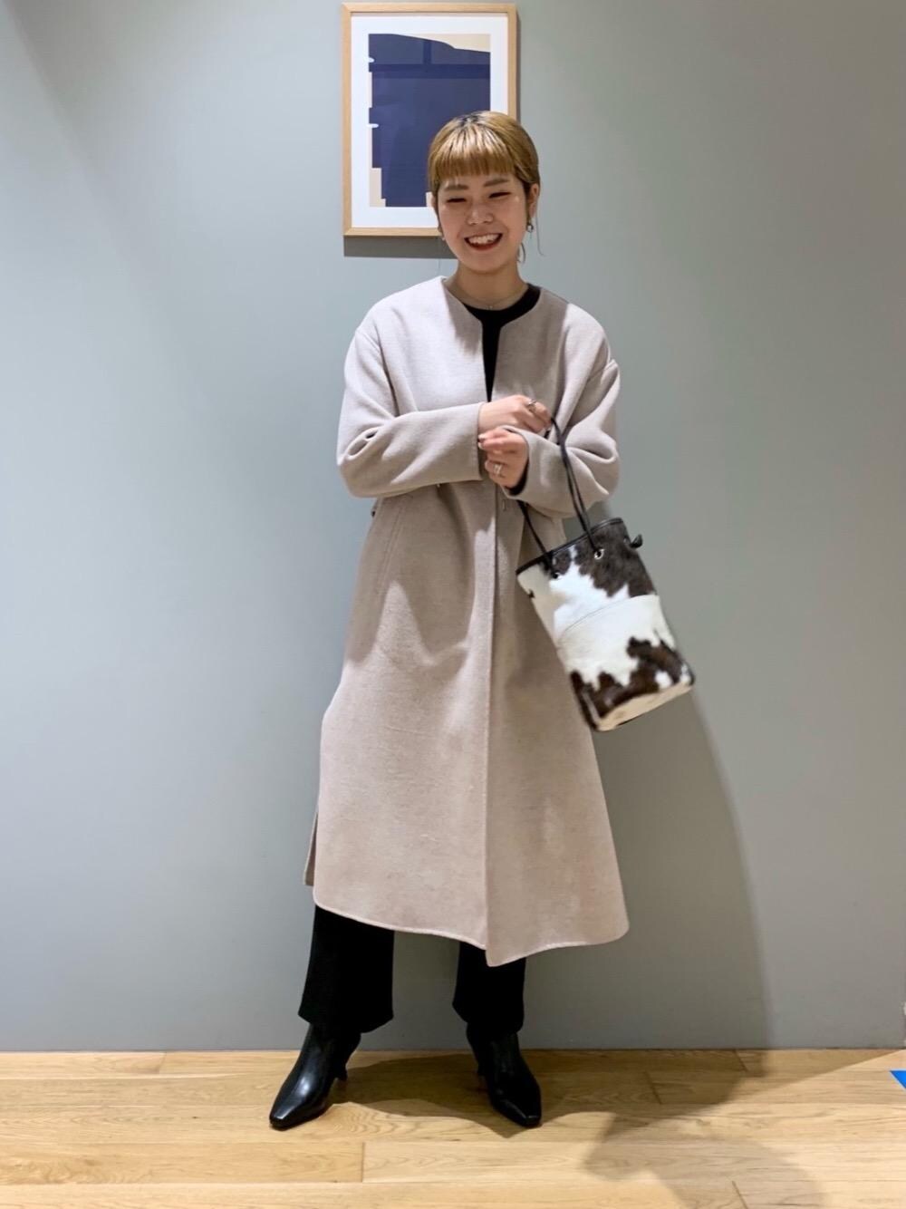 ブラウン系のニット/セーター、ブラック系のブーツ、ベージュ系のノーカラーコートを着用したレディースの秋コーディネートの1枚目の写真