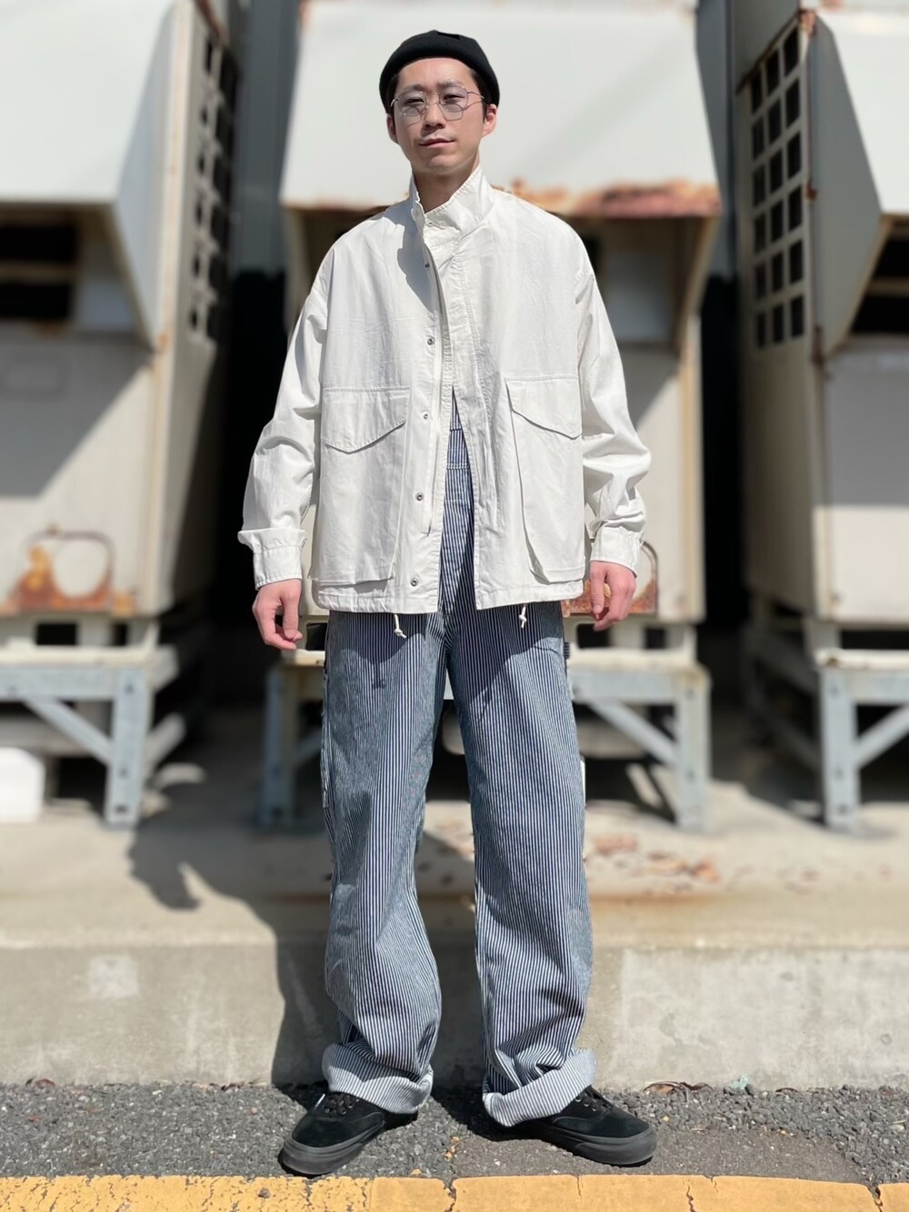 ホワイト系のミリタリージャケット、ブルー系のオールインワン・サロペット、ブラック系のシューズを着用したメンズの春コーディネートの1枚目の写真