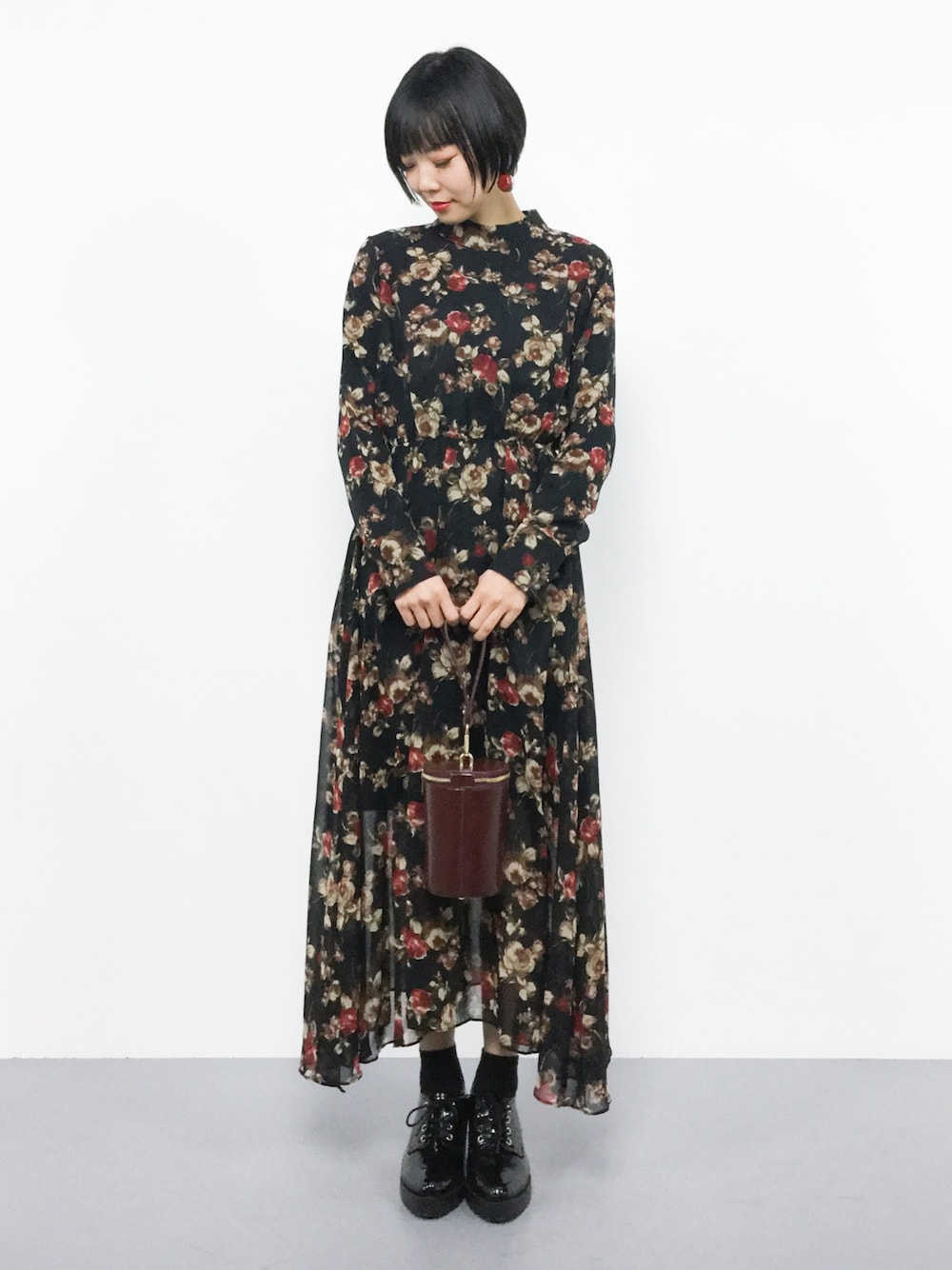 ブラック系のワンピース、レッド系のショルダーバッグを着用したレディースの冬コーディネートの1枚目の写真