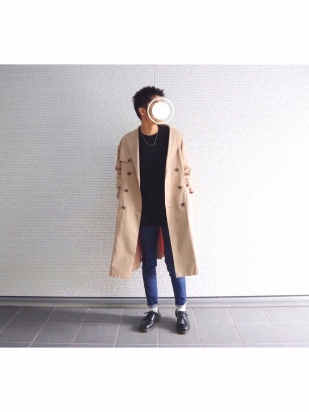 ベージュ系のトレンチコート、ブラック系のTシャツ/カットソー、ブルー系のデニムパンツを着用したメンズの冬コーディネートの1枚目の写真